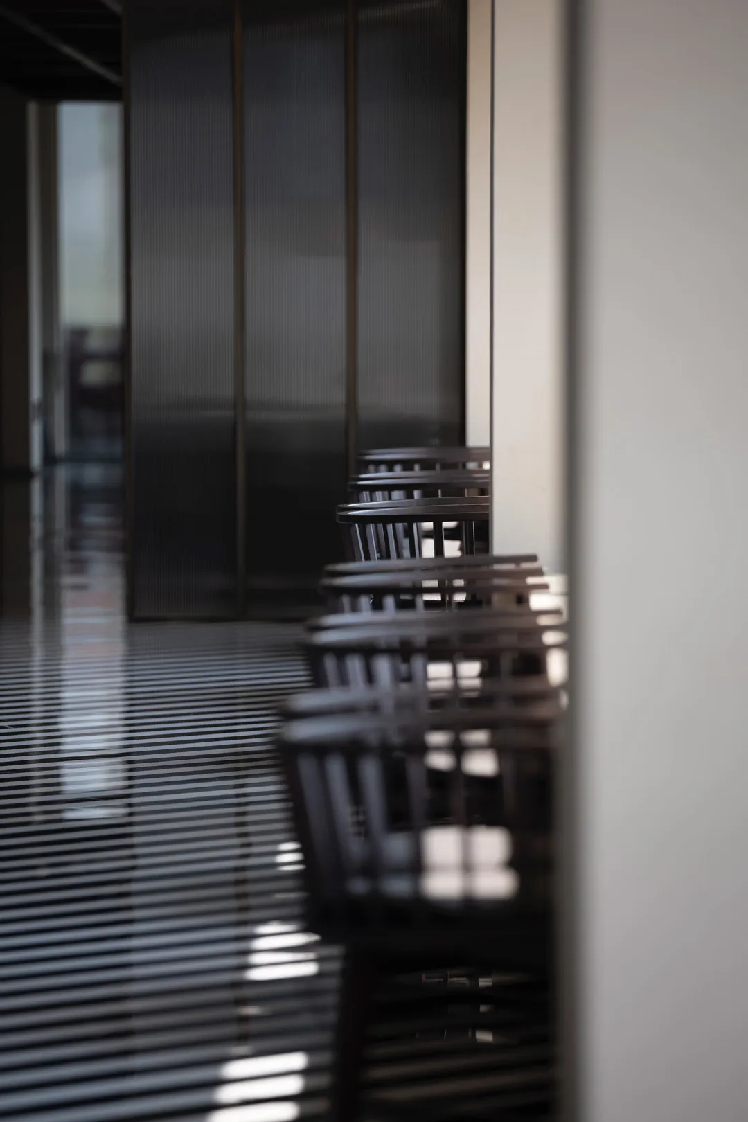 A row of wooden dining chairs arranged in a restaurant interior. The chairs have a minimalist design and are set against a sl