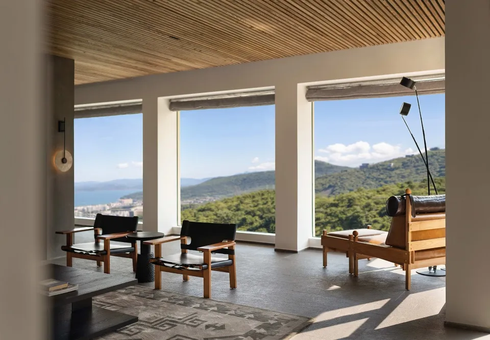 A modern living room with wooden furniture, glass windows, and leather accents.