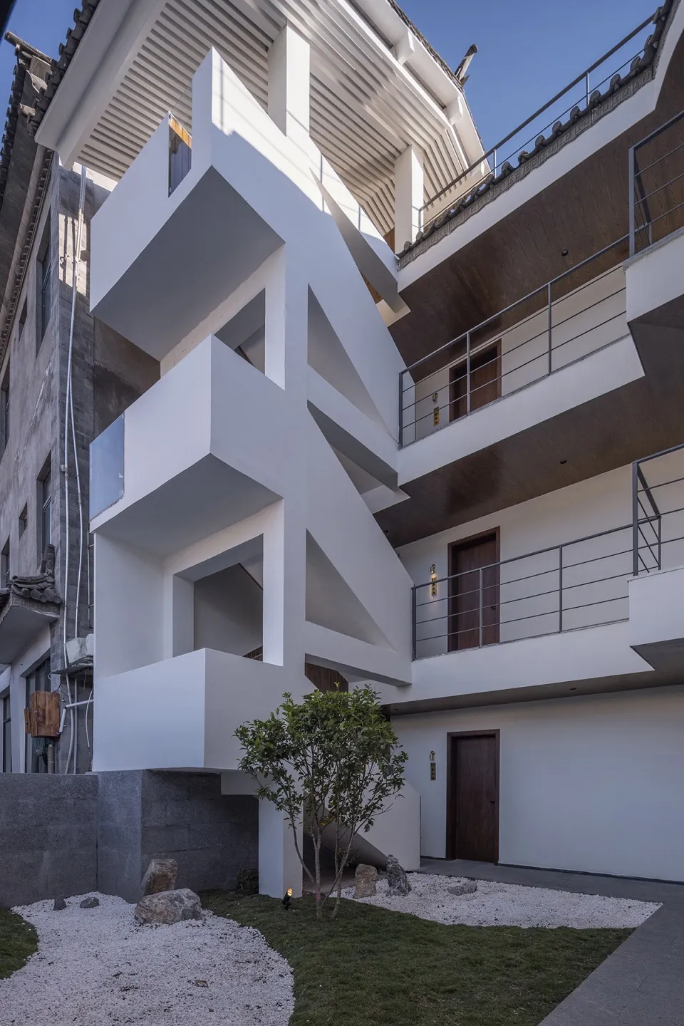 Modern residential exterior featuring minimalist design with white concrete walls and glass elements.