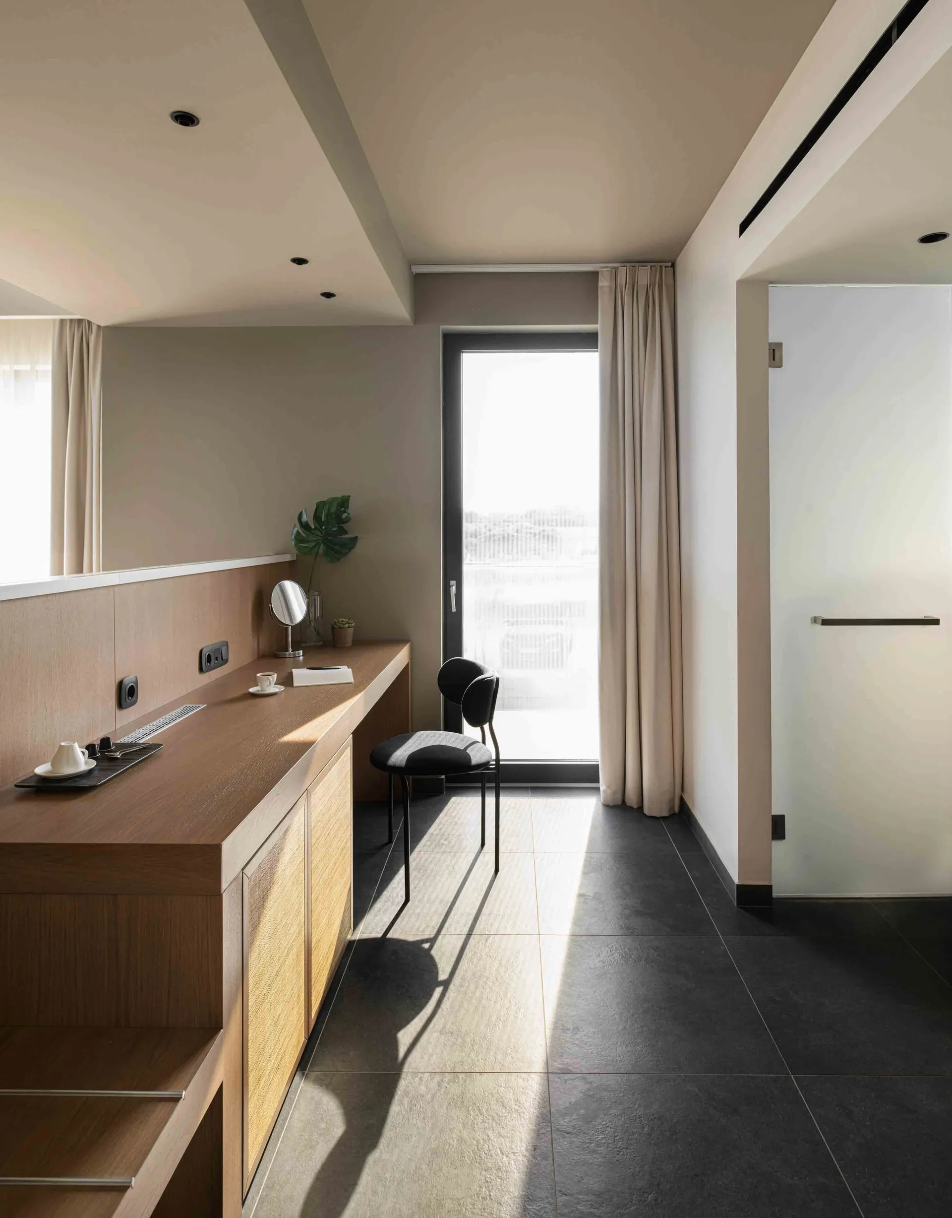 A modern residential interior featuring wooden furniture, concrete flooring, and glass doors.