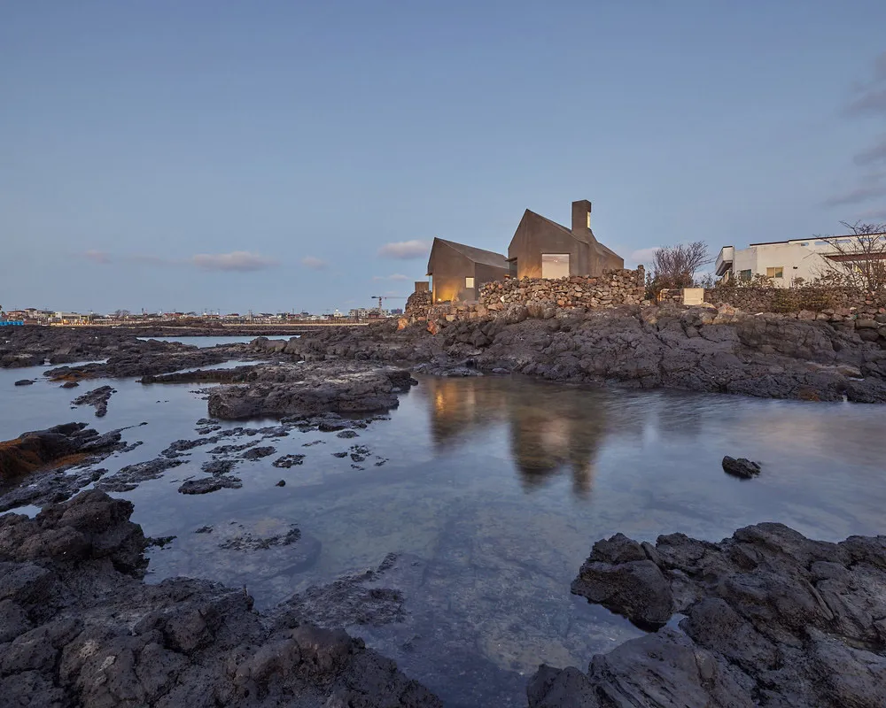 一座以石材建造的現代住宅建築，坐落於岩石河岸之上。