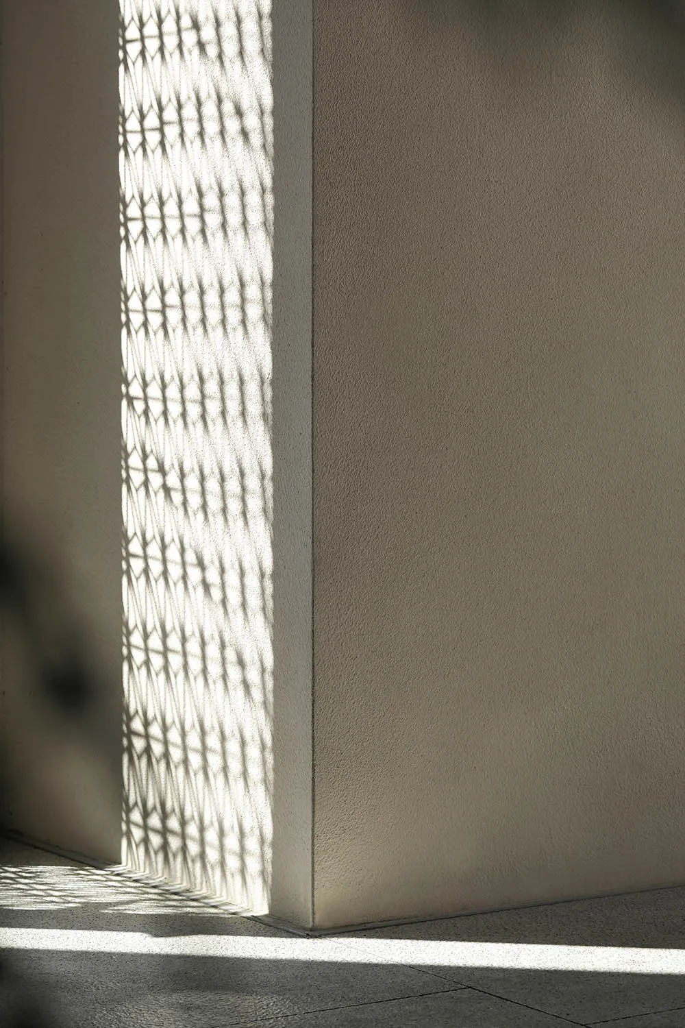 A minimalist architectural design with a shadow pattern on a textured wall.