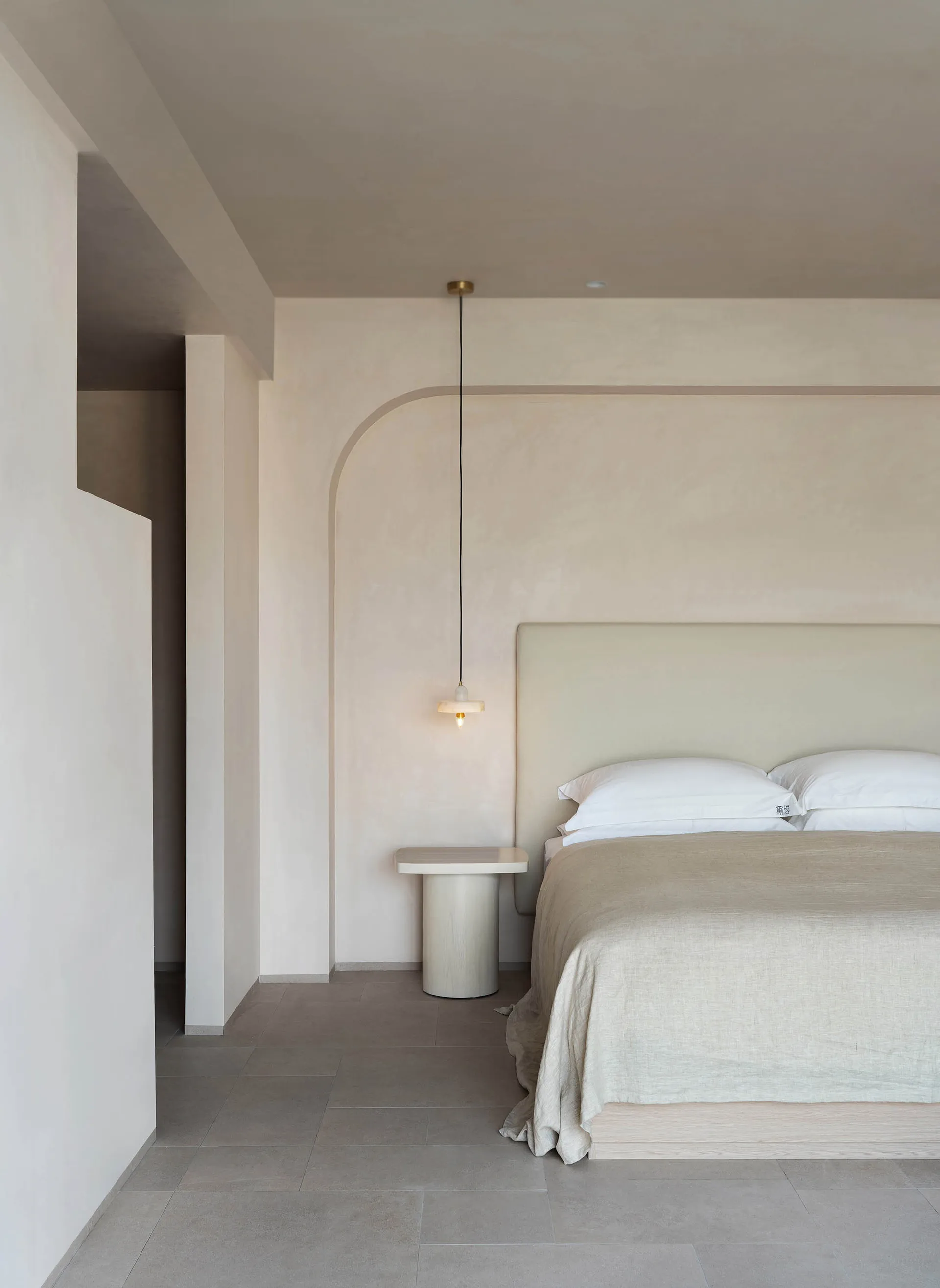 Minimalist bedroom with concrete sconce and concrete floor.