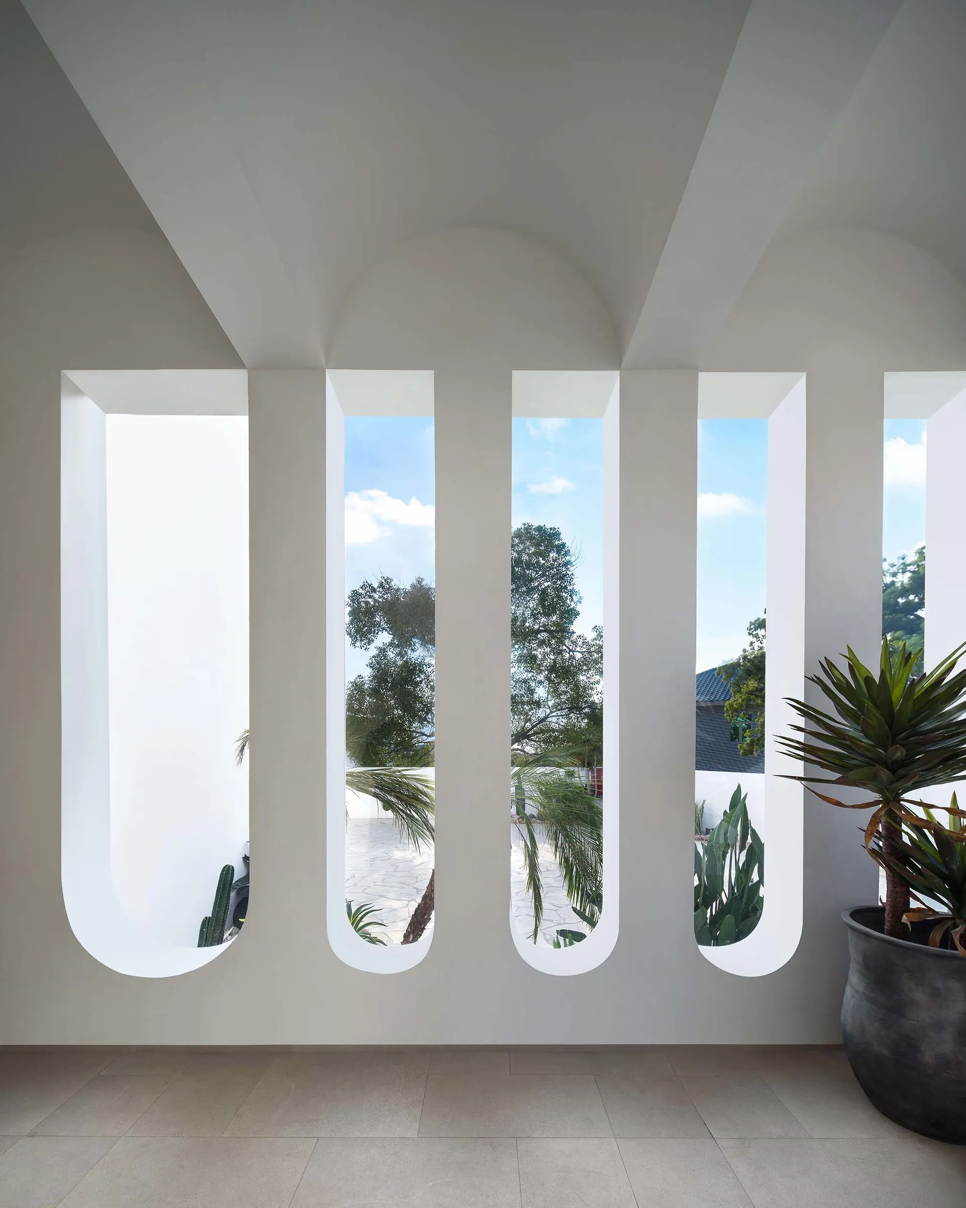 Modern interior design featuring a wall of arched windows with white plaster.
