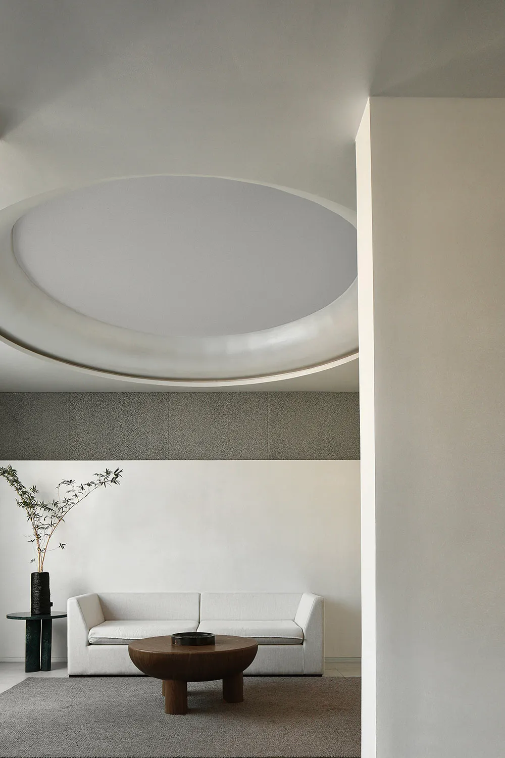 Modern living room with neutral tones, featuring a round coffee table and a serene indoor plant.