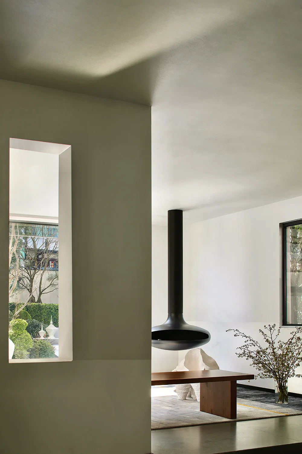 A modern minimalist living room with concrete and wooden elements.