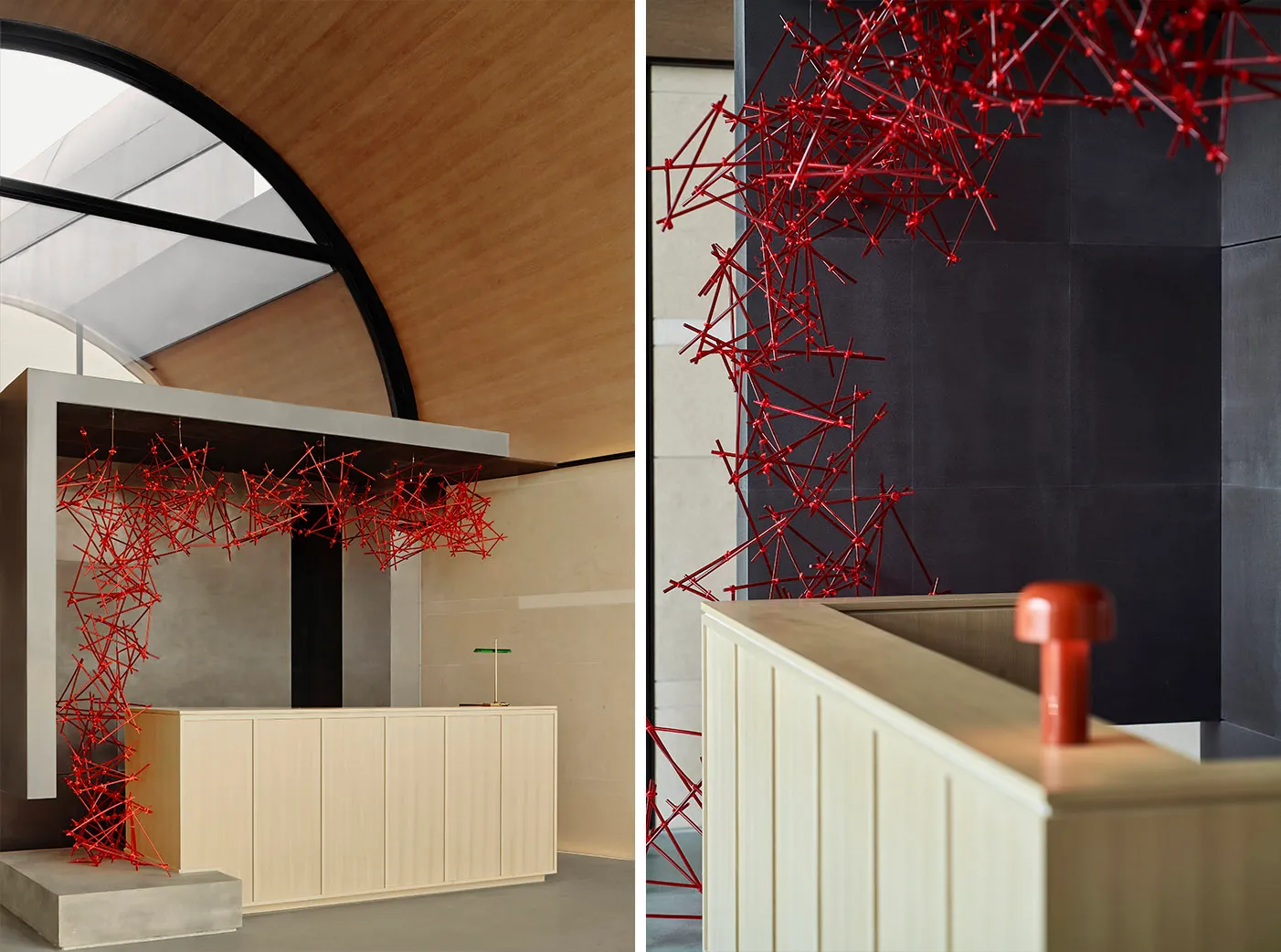 A modern reception desk with a red metallic network design against a dark and white tiled background.