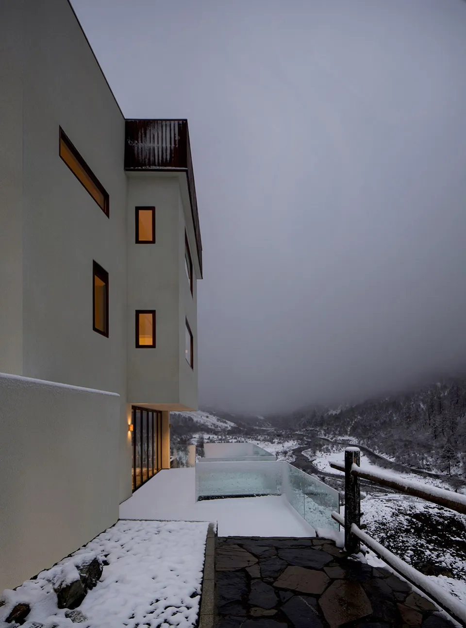 現代住宅建築，外牆雪白，屋頂與景觀覆蓋白雪。