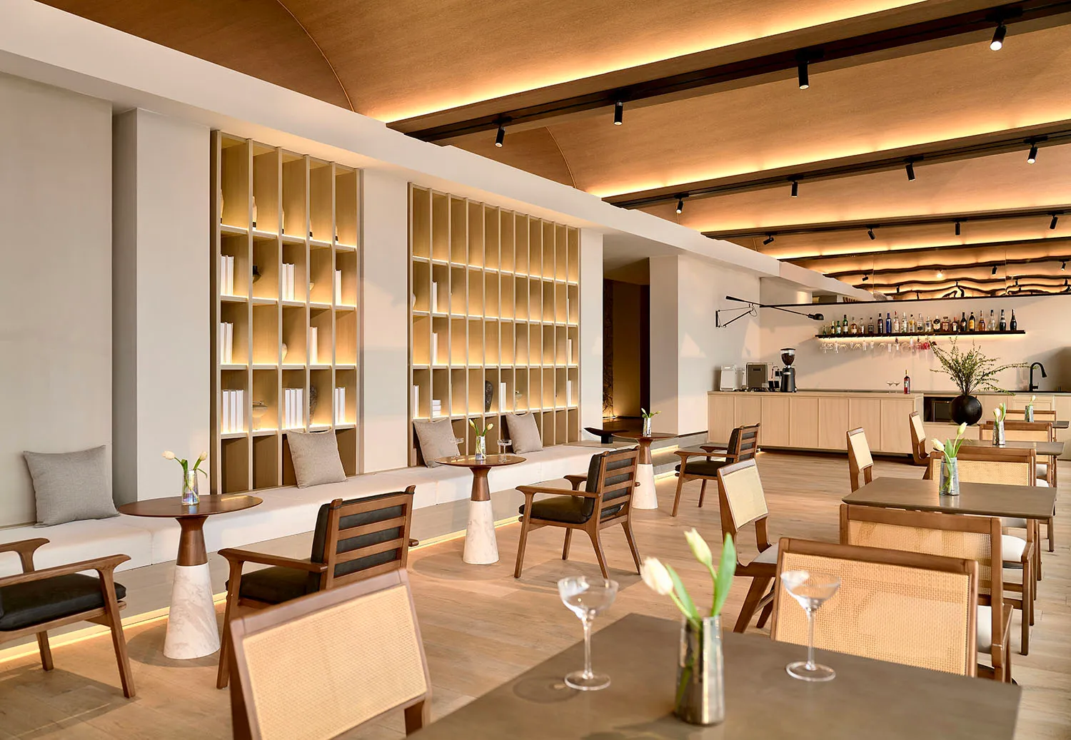 An elegant modern restaurant and bar interior featuring wooden furniture, marble accents, and glass displays.