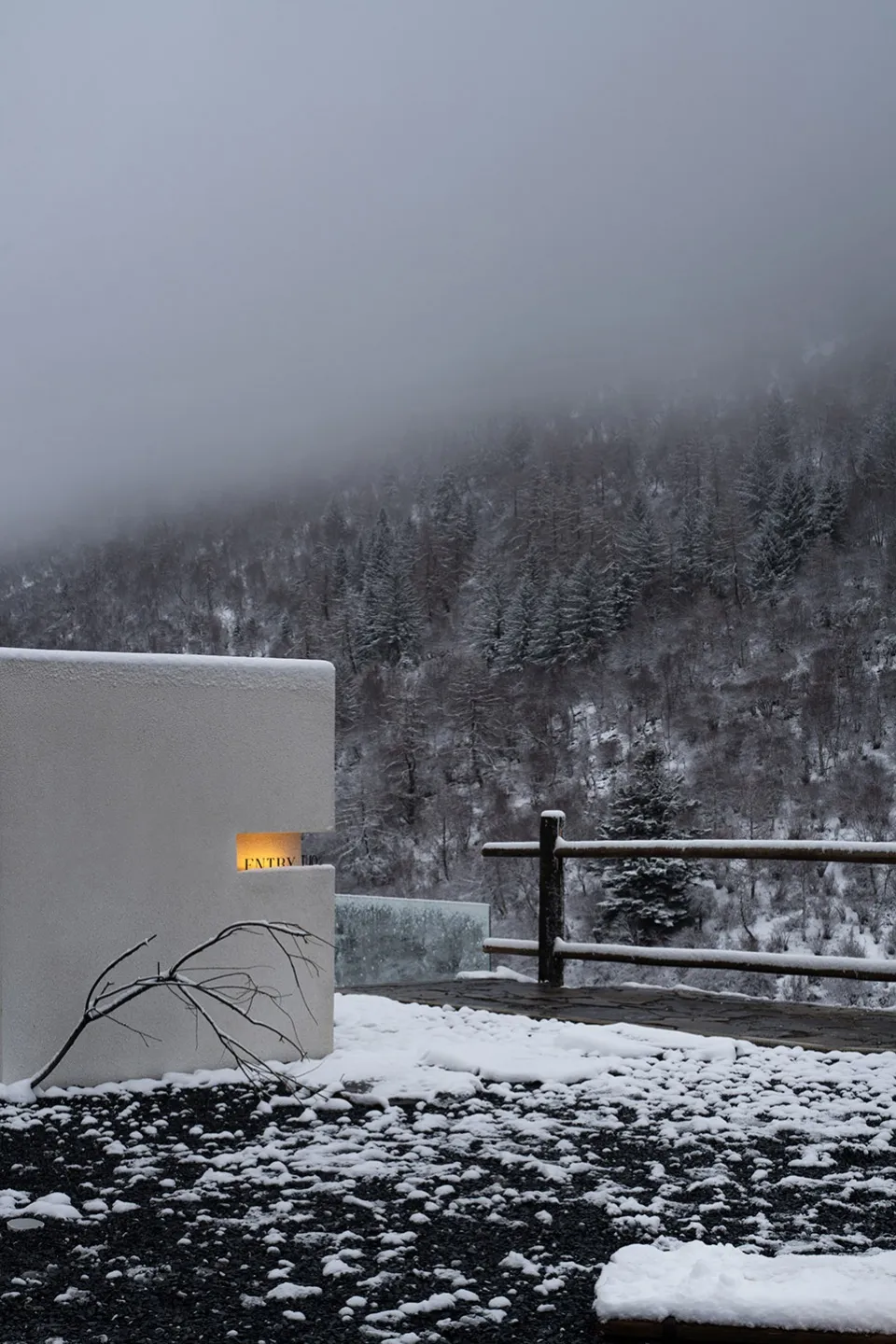 極簡白色建築物被雪景環繞,周圍有木製圍欄。