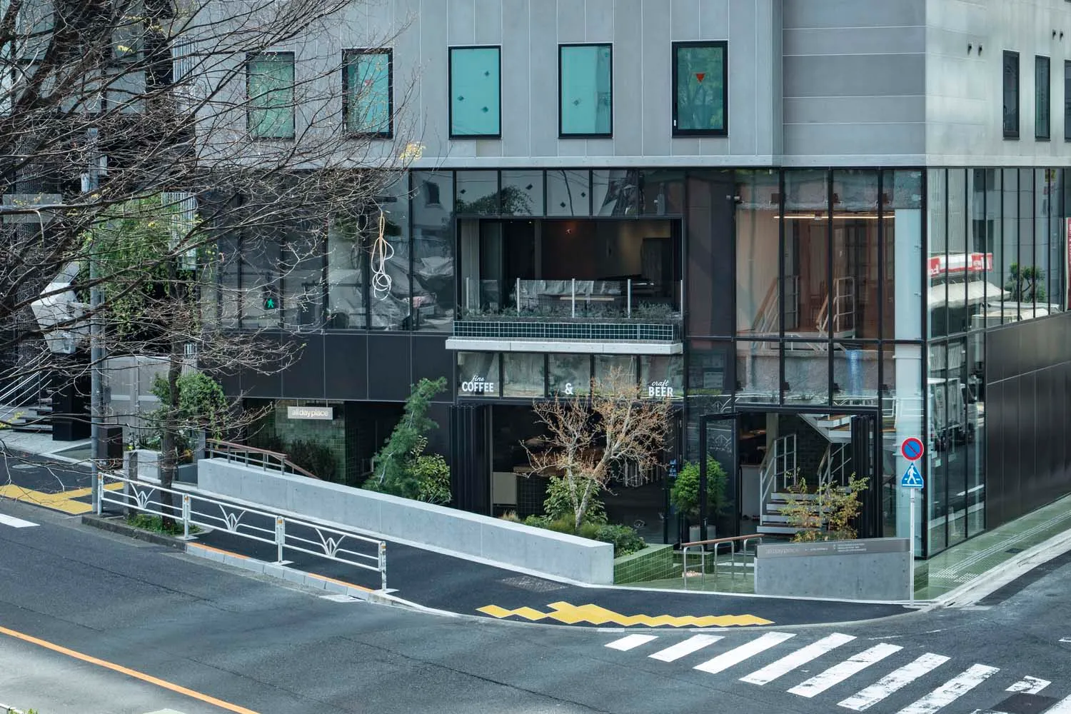 Modern city coffee shop facade with glass front and greenery.