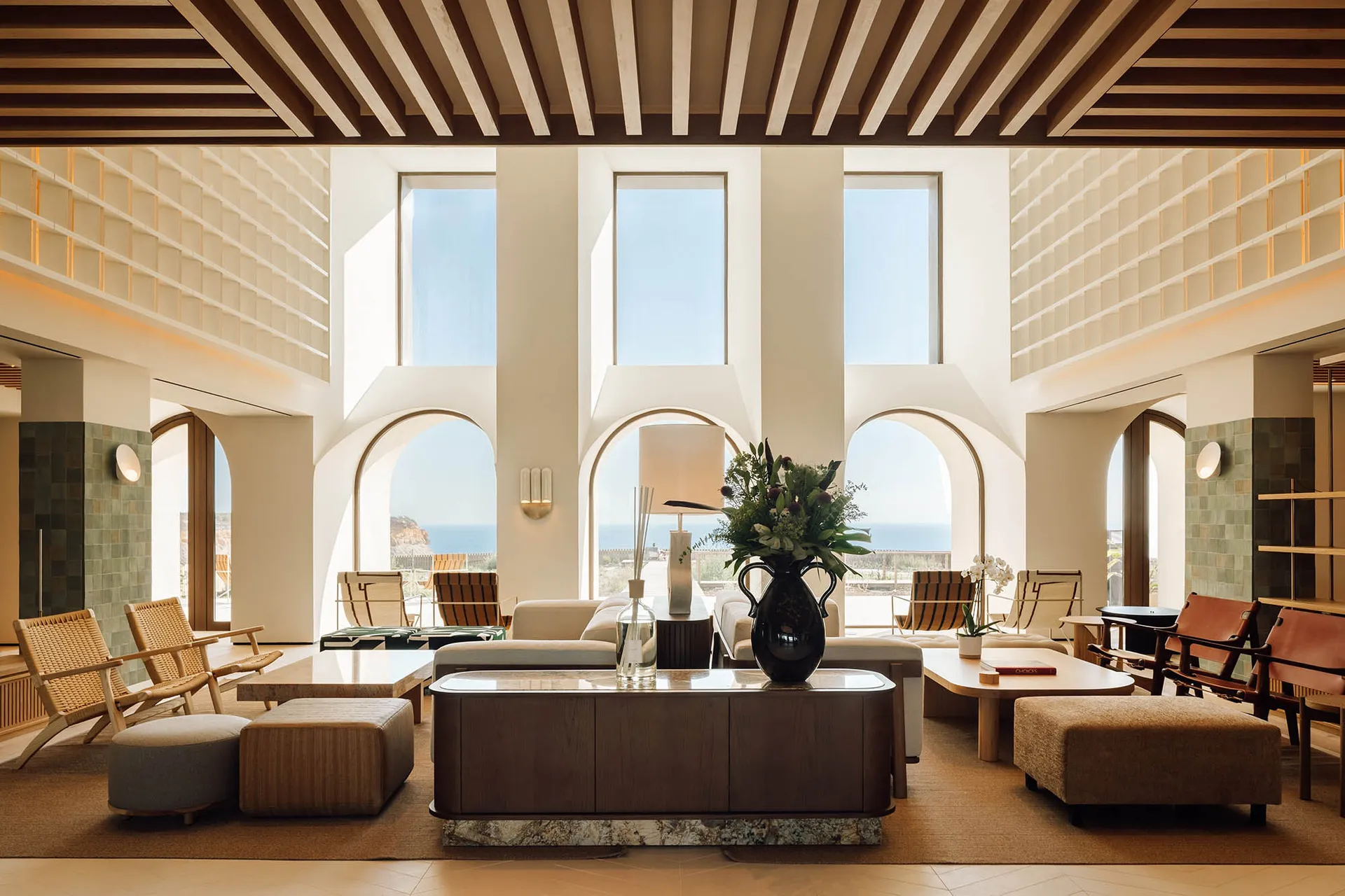 A modern hotel lobby featuring natural light through large windows and contemporary furniture.