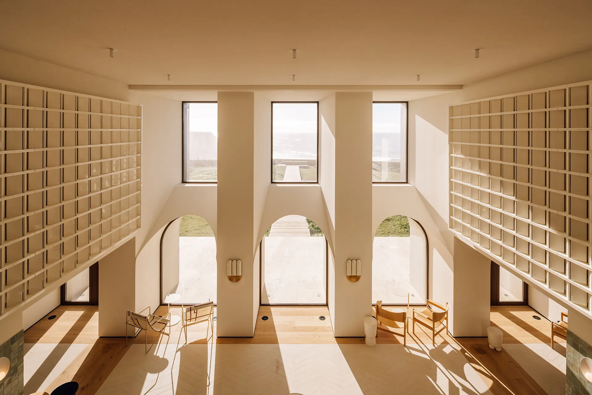 Modern interior design featuring exposed concrete walls, large windows, and warm lighting.