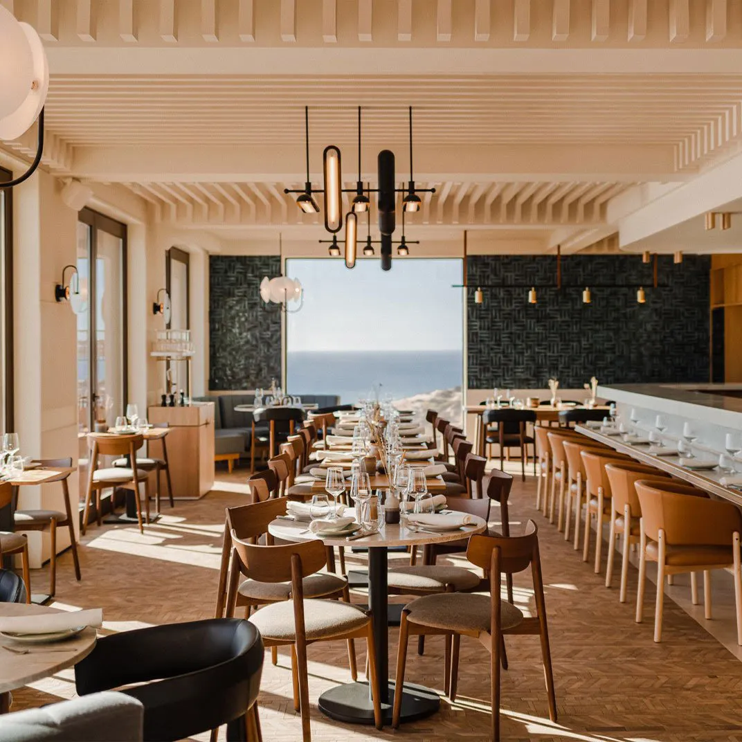 Modern restaurant interior featuring natural wood accents and an ocean view.