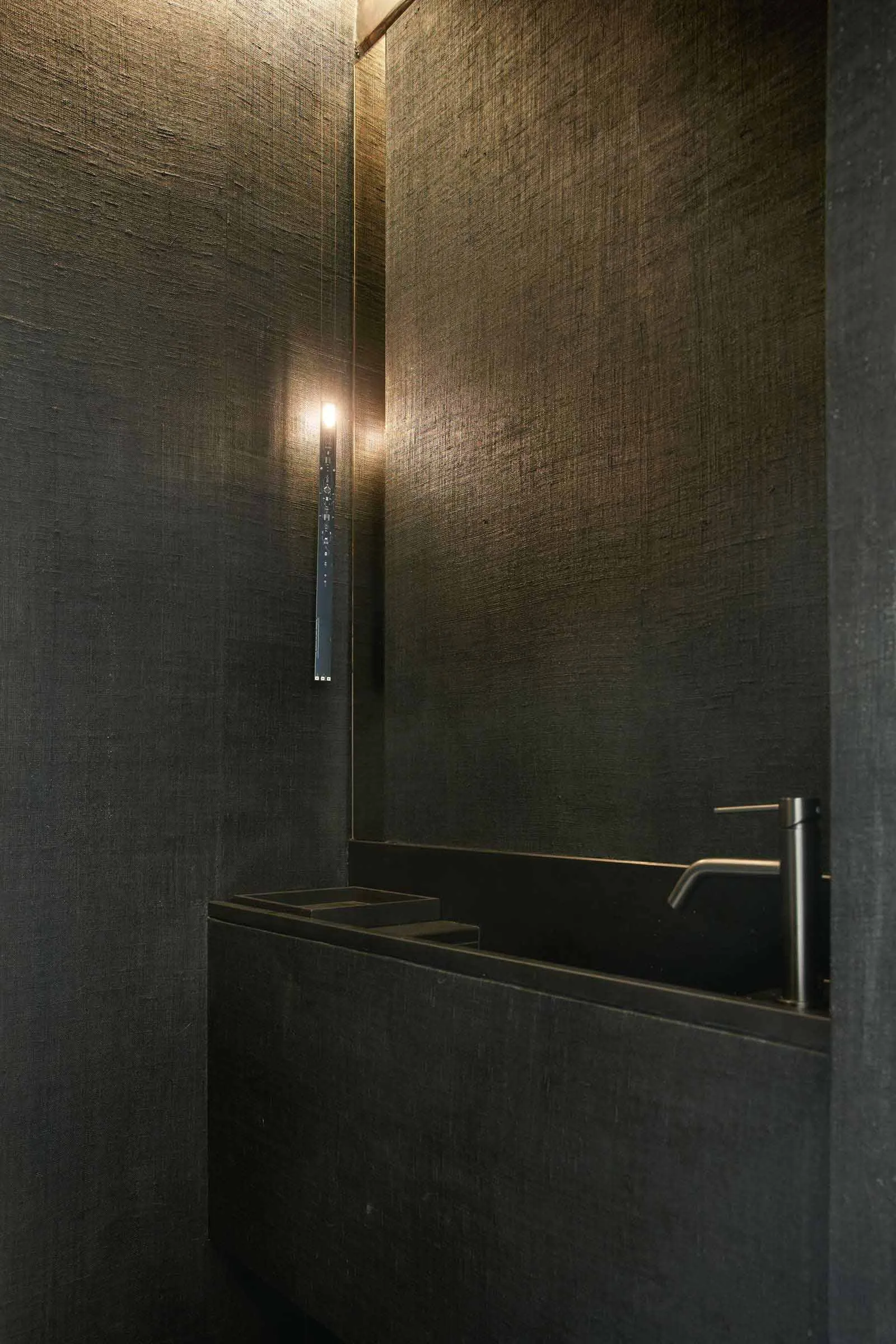 A minimalist bathroom with concrete walls and a sink.