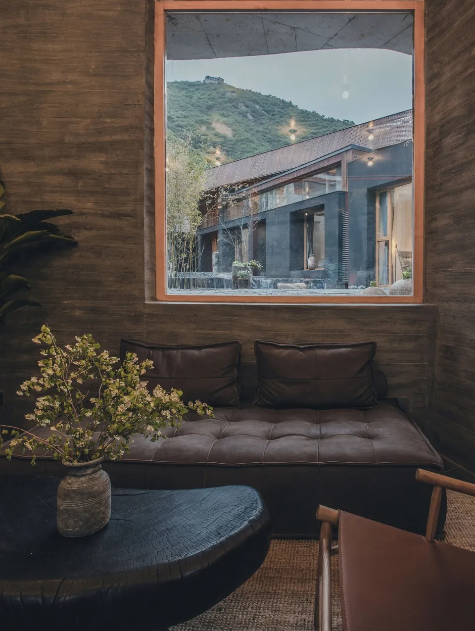 Modern living room featuring a leather sofa, glass windows, and wooden textures.