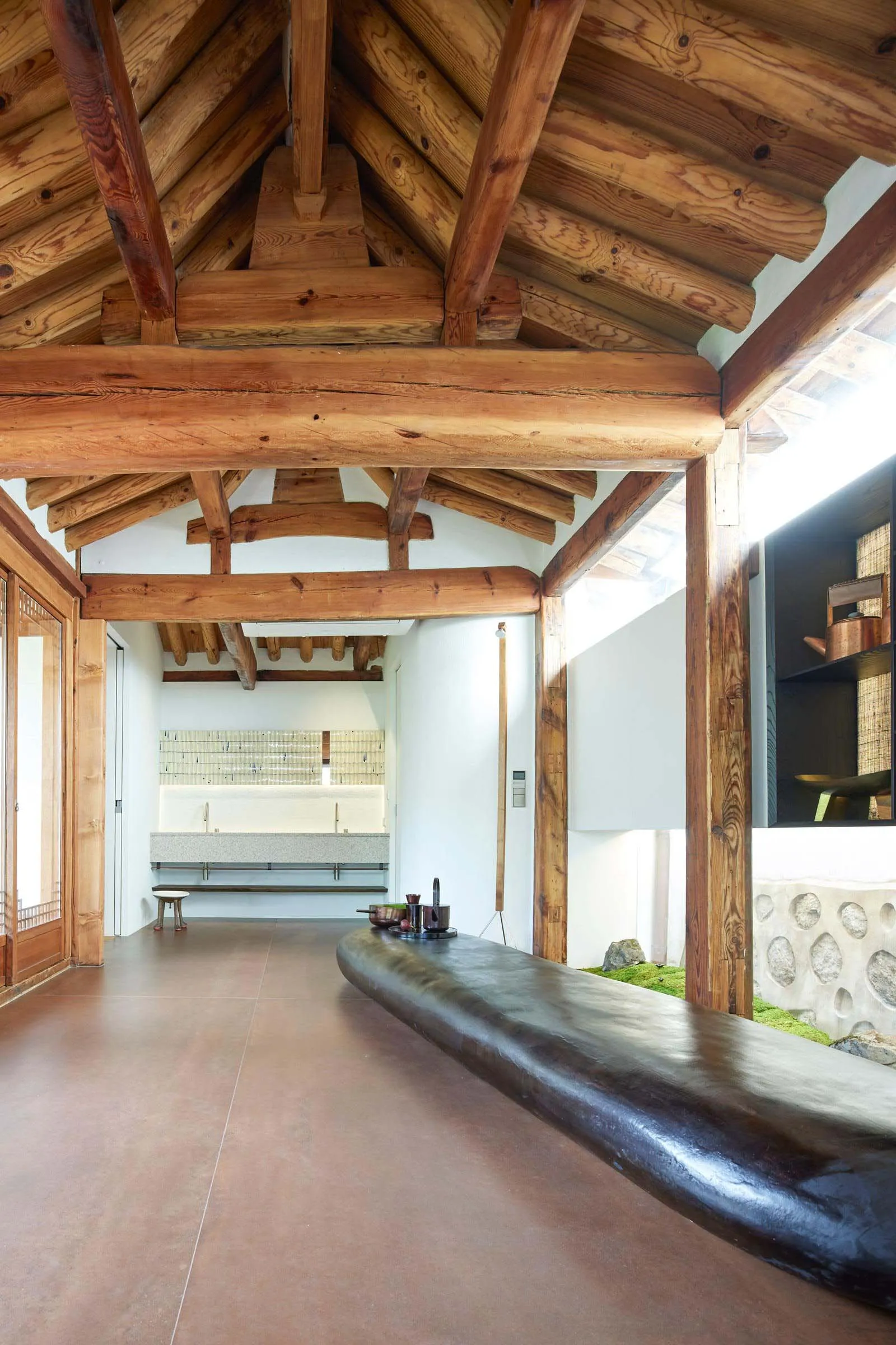 Modern minimalist interior space with exposed wooden beams and natural lighting.