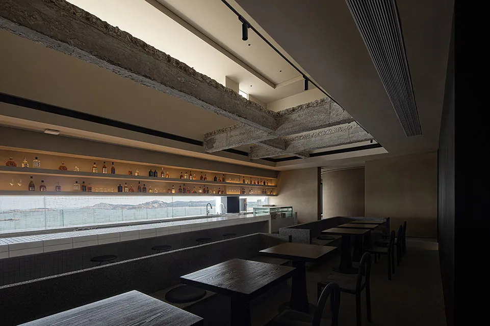 A modern bar interior with concrete counter and seating areas