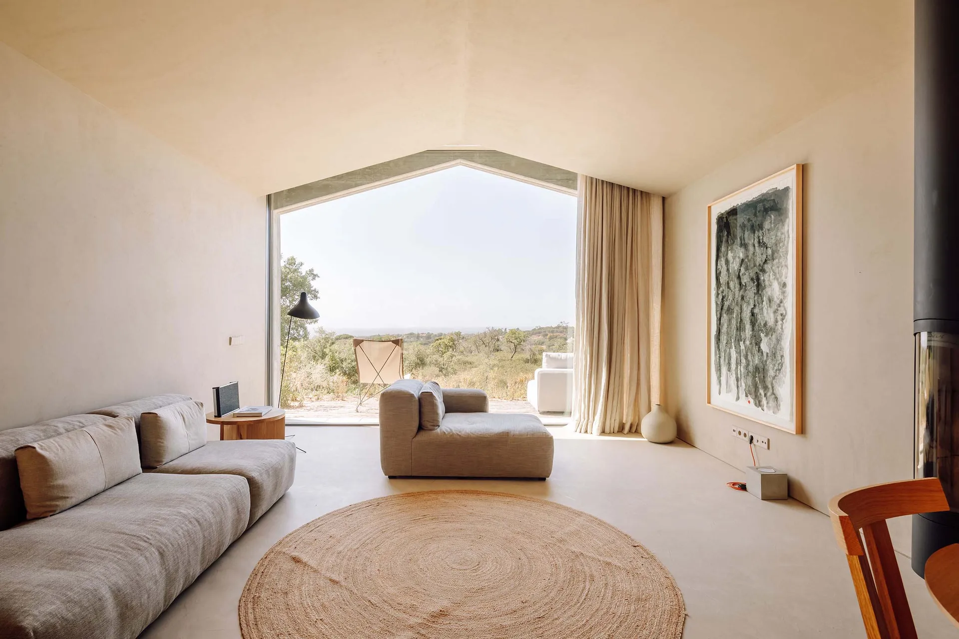 A living room with a minimalist sofa, large windows, and natural light.