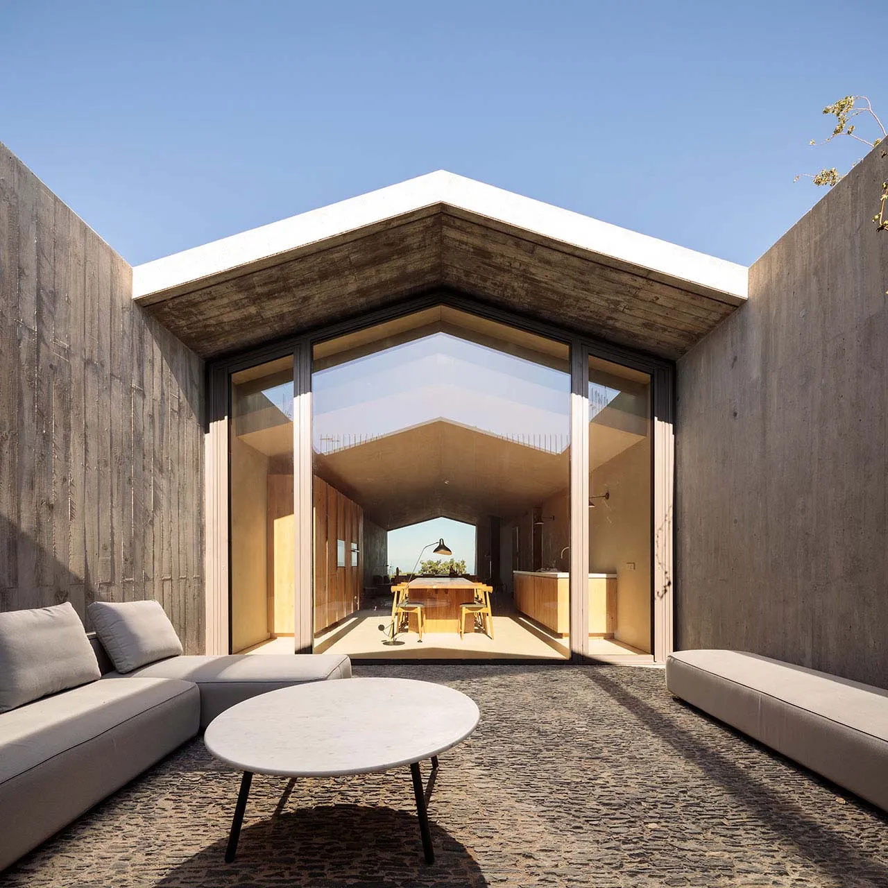 Modern living room with concrete walls and large glass windows.
