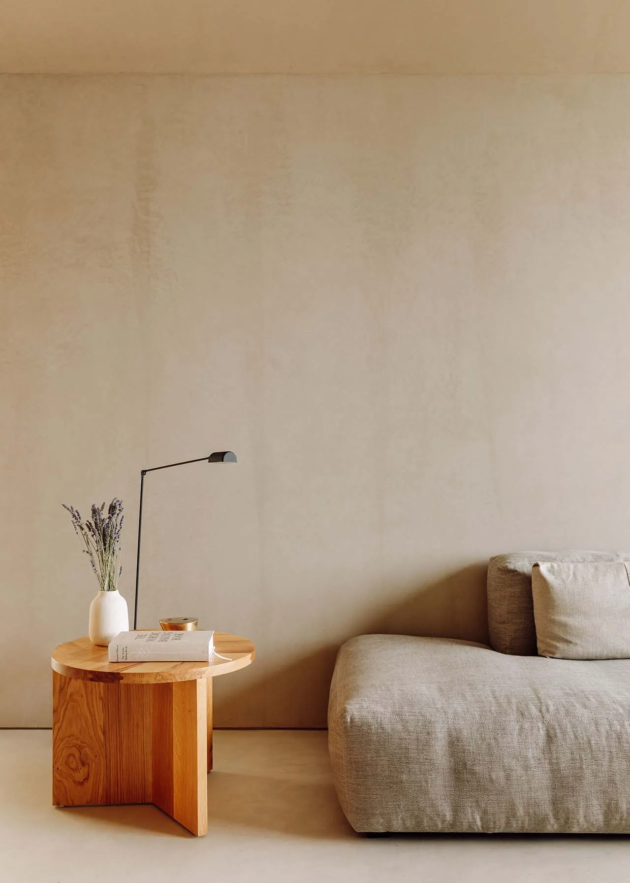 A cozy living room with neutral tones, featuring a modern sofa, wooden table, and floor lamp.