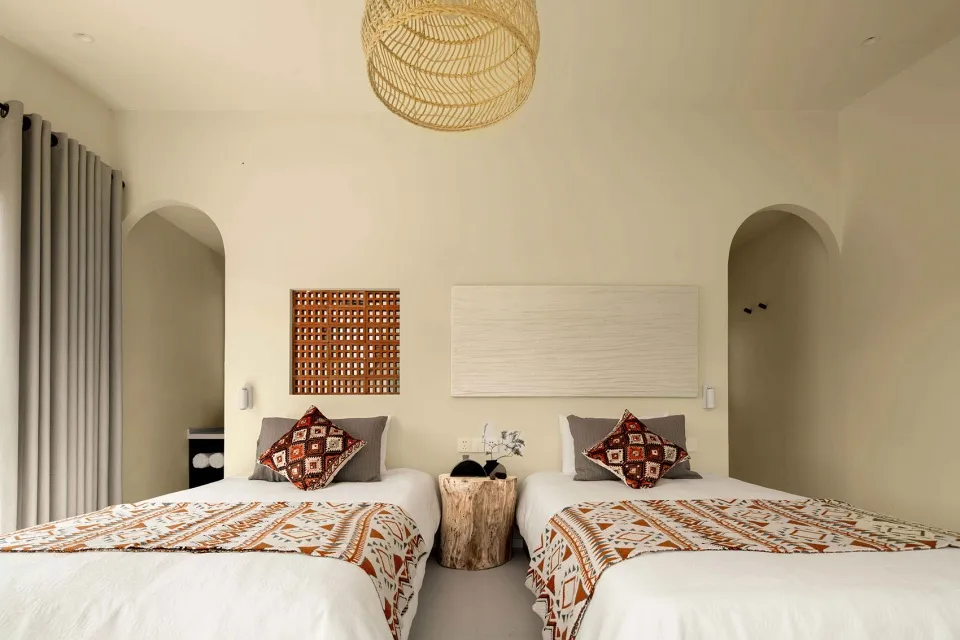 Modern bedroom with wooden headboards, textile bedding, and decorative cushions.