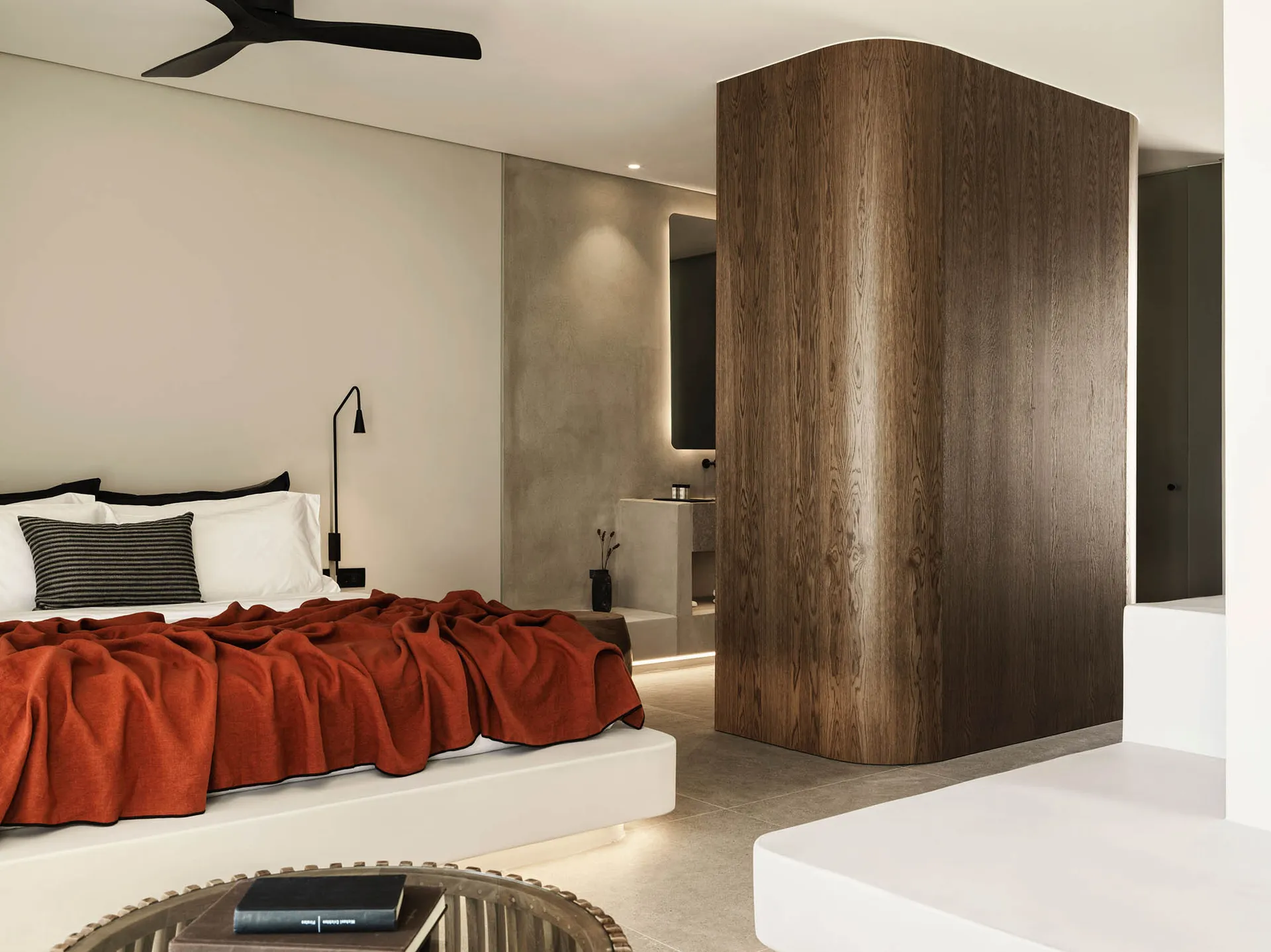 A minimalist bedroom with a wooden wall and red blanket on the bed.