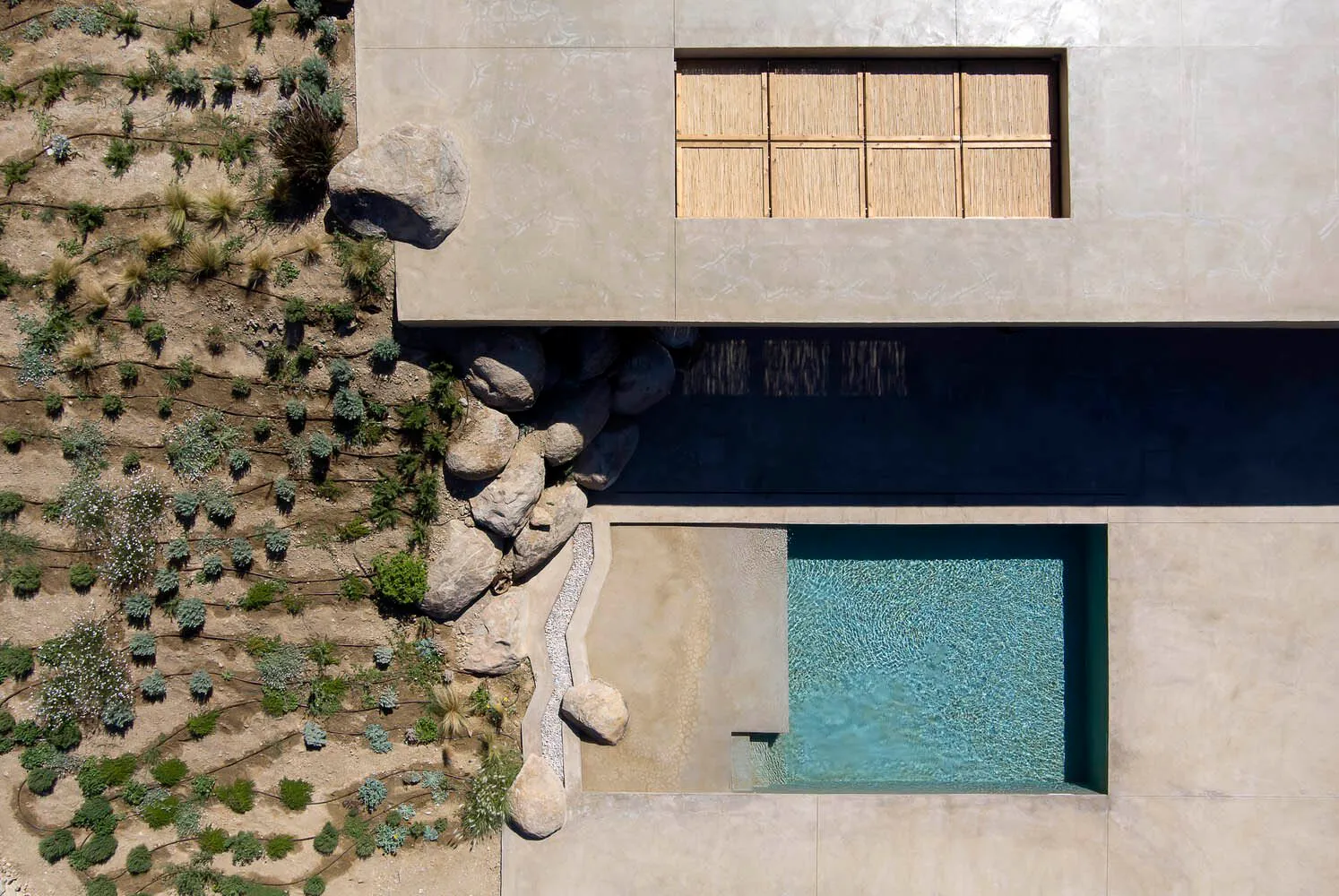 An aerial view of a modern residential space featuring a concrete and glass pool design.