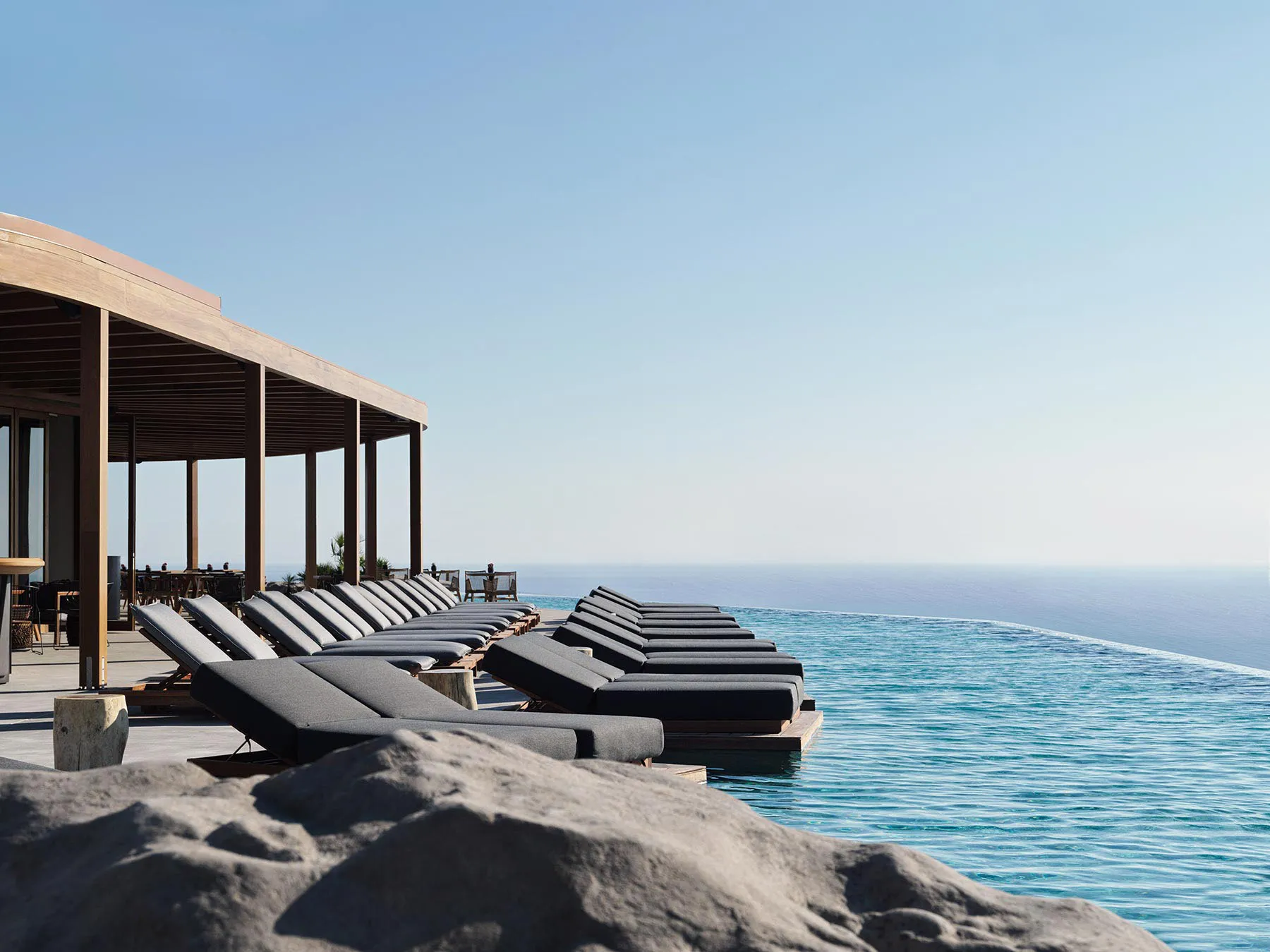 Modern minimalist swimming pool area with concrete deck and glass infinity edge pool.