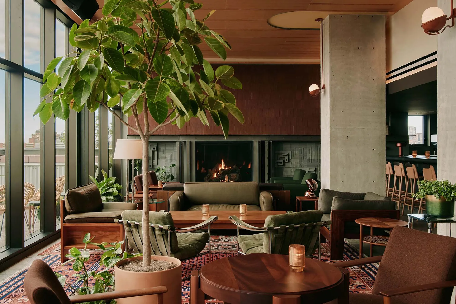 A modern hotel lobby featuring concrete and wood materials with a cozy fireplace and comfortable seating.