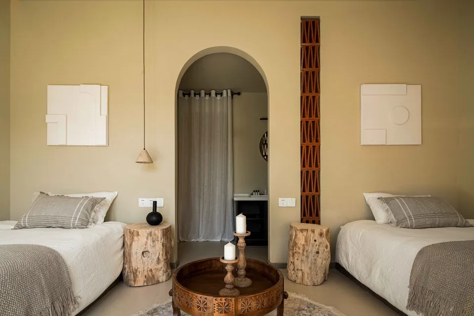 A minimalist bedroom with earth-toned bedding, wooden furniture, and decorative elements.