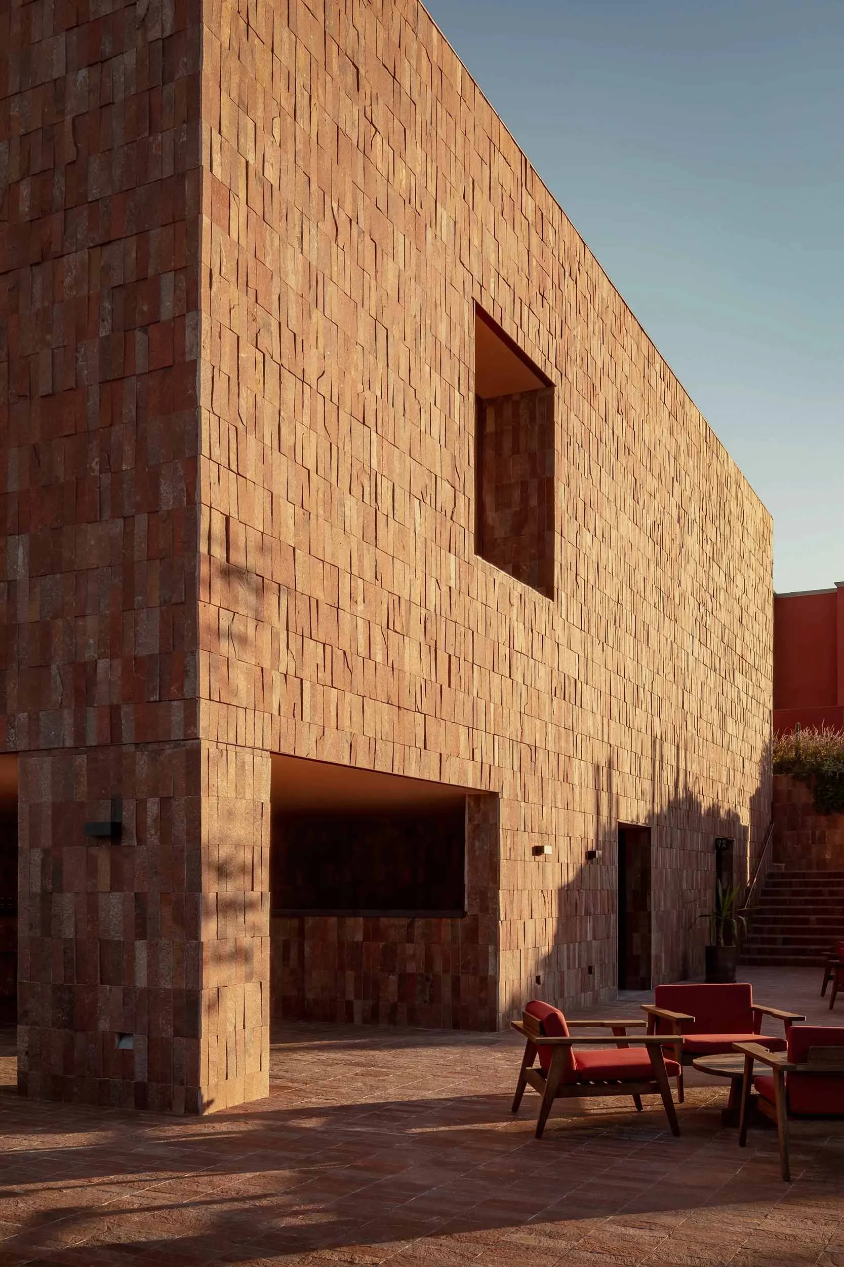 A modern building made of red bricks with a paved courtyard.