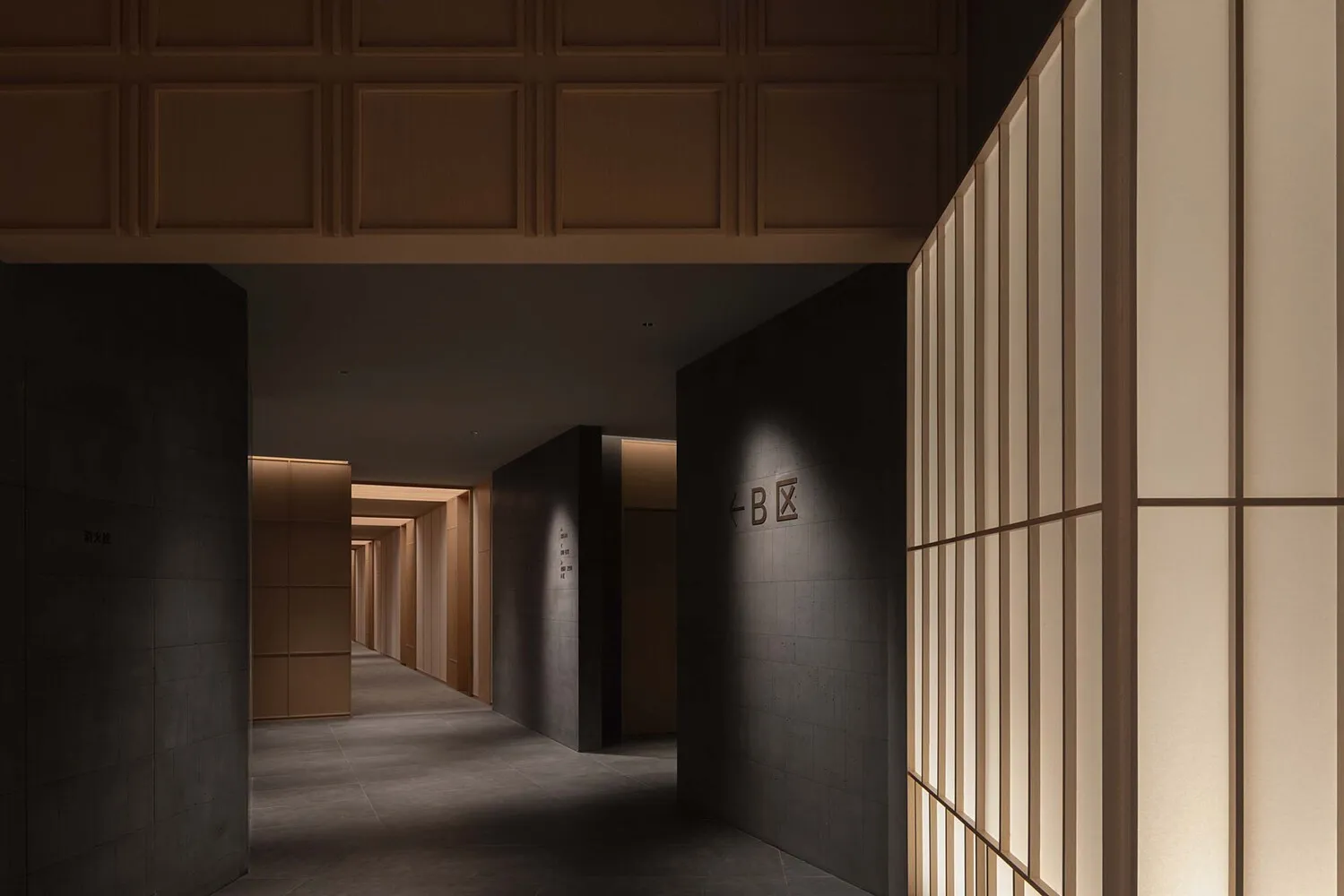 A minimalist hotel corridor featuring concrete and wooden walls.