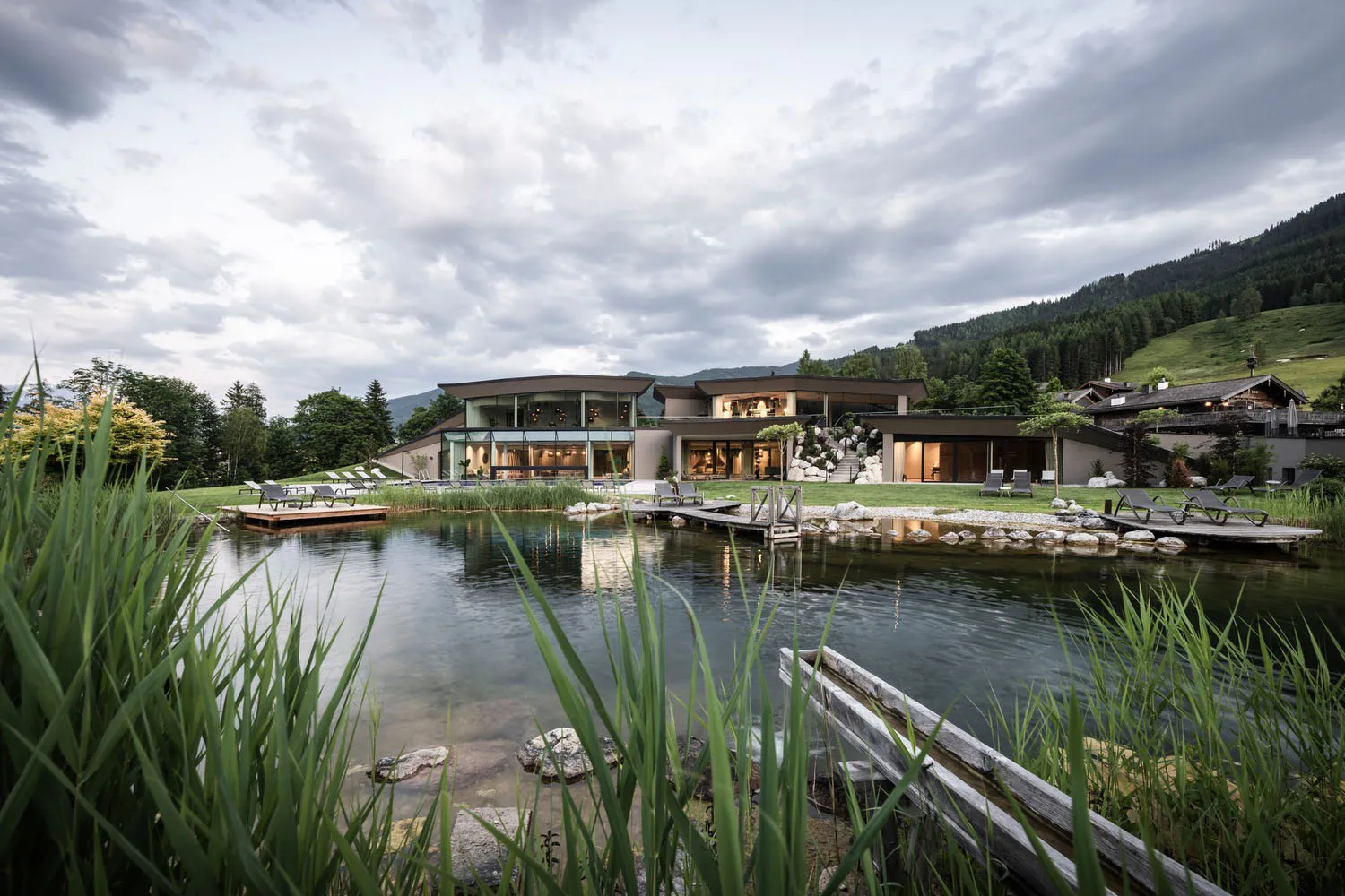 A modern architectural residence featuring glass walls and stone pathways by a serene water feature.