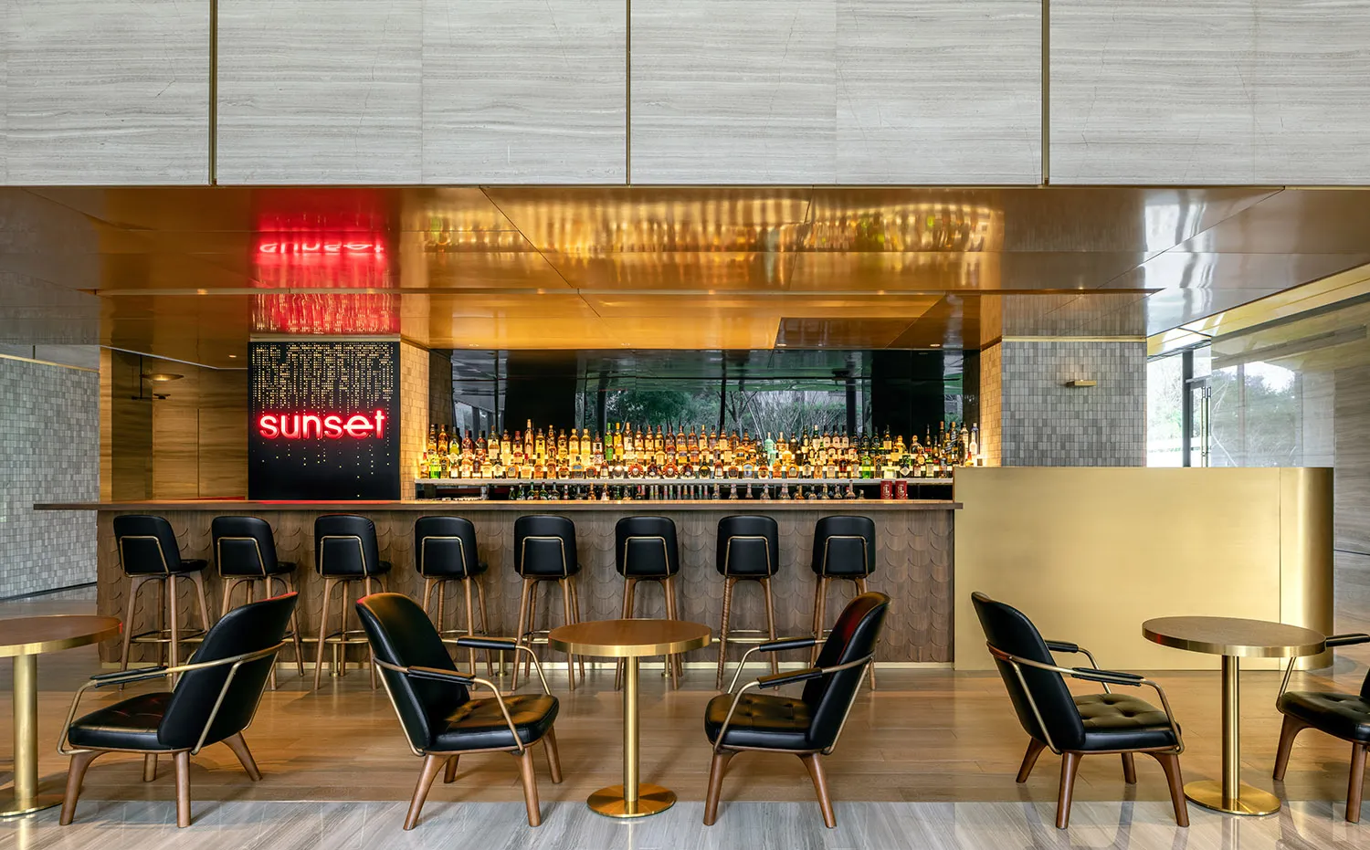 A sleek, modern bar area with metallic surfaces and a large assortment of liquor bottles.