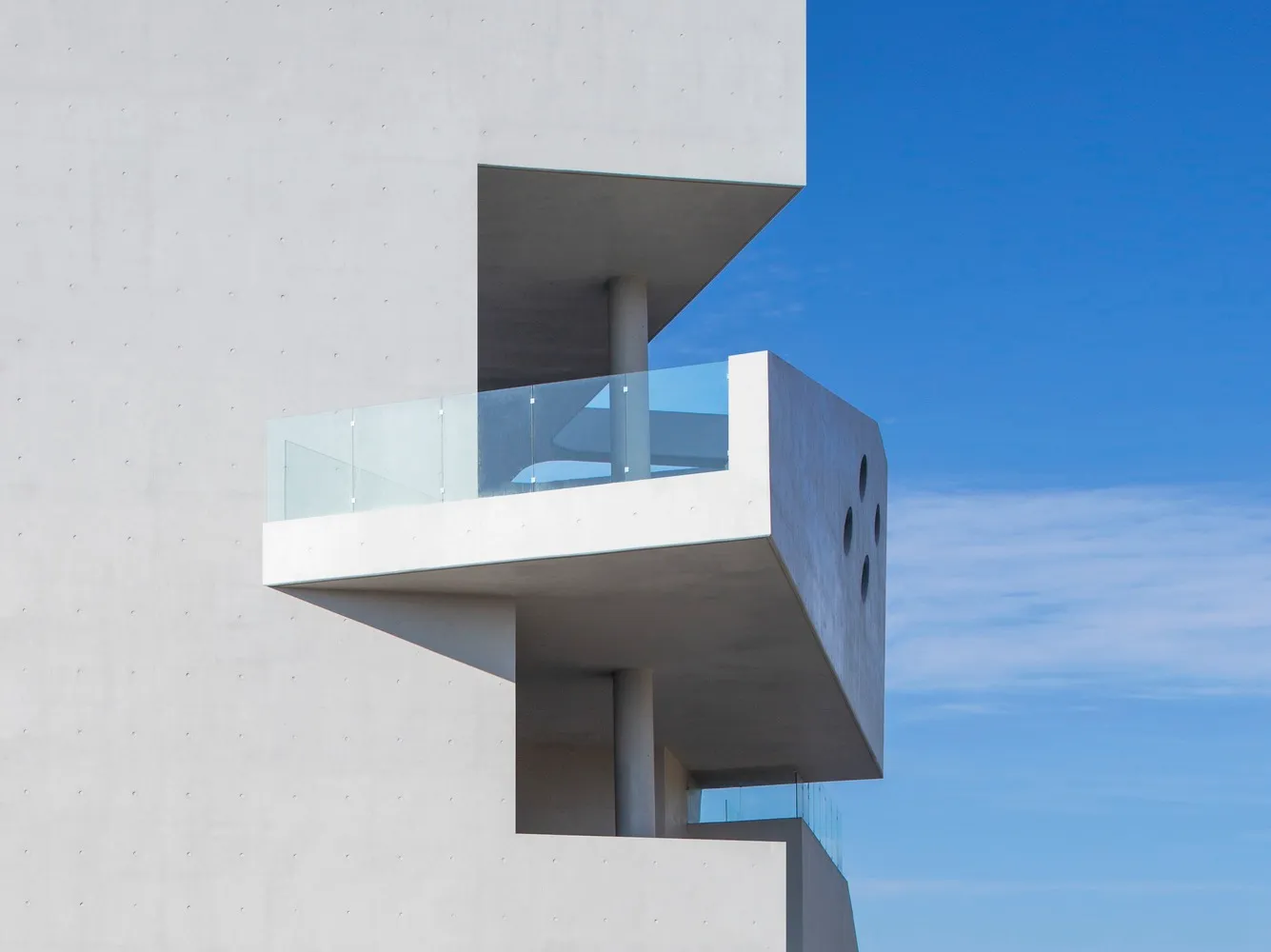Modern concrete facade with glass balcony.