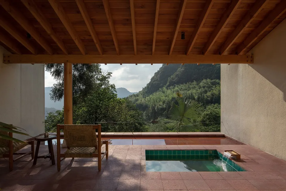 A modern minimalist patio featuring a swimming pool surrounded by a tiled floor and wooden beams.