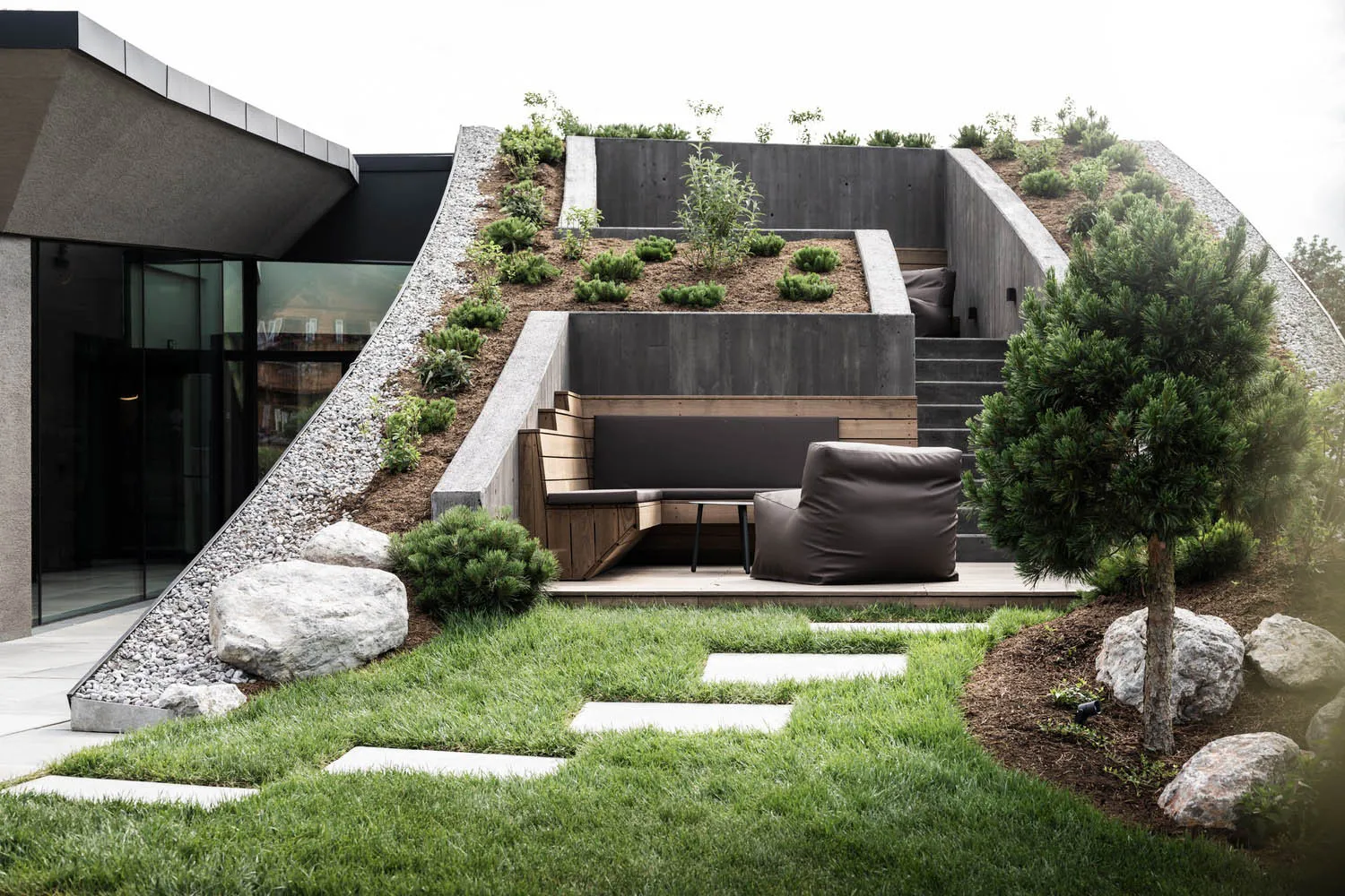 A modern outdoor space featuring concrete steps, wooden seating, and grass