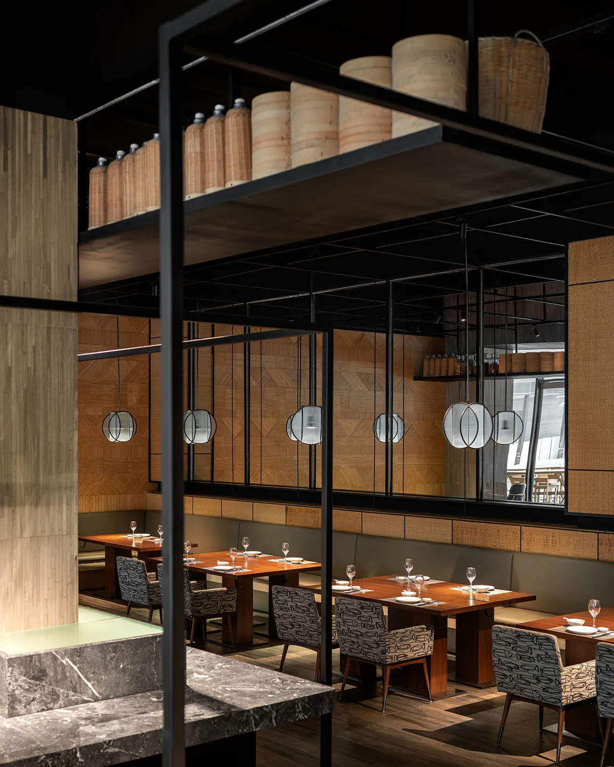 A modern restaurant interior with wooden tables, metal chairs, and glass elements.