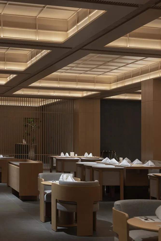 Modern restaurant interior with wooden tables and chairs, elegant lighting, and minimalist design