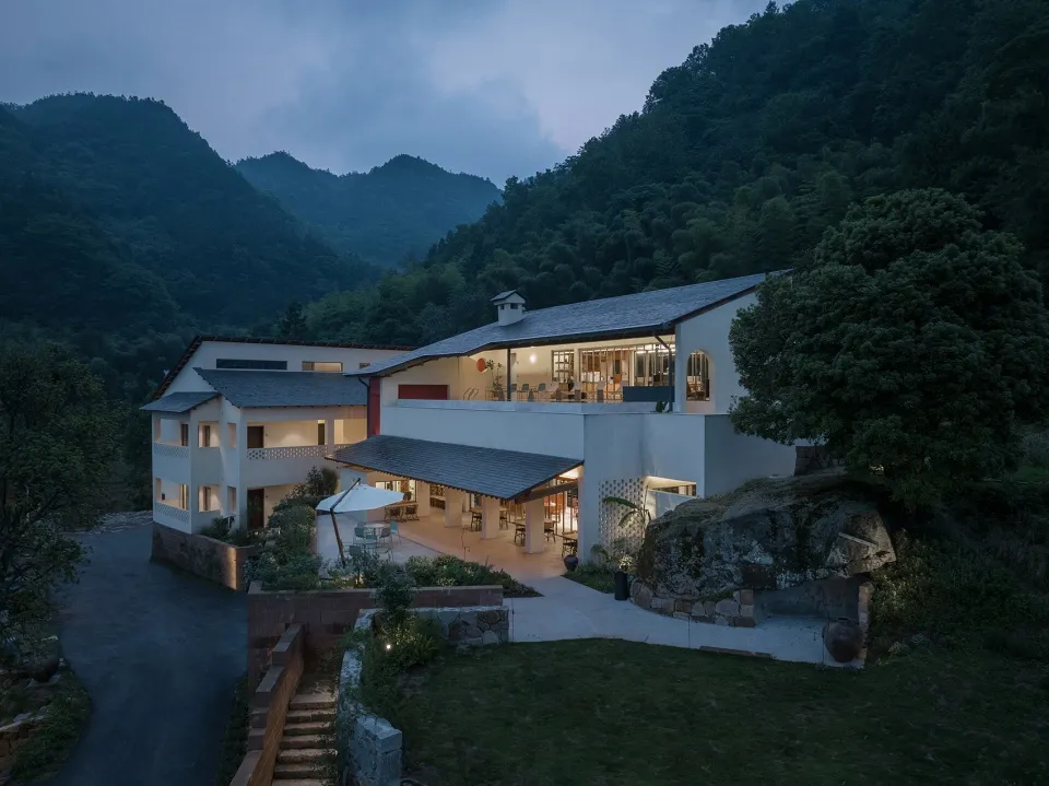 A modern mountain residence featuring concrete and glass materials in a serene outdoor setting.