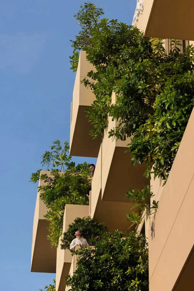 Apartment building with green balconies covered in lush vegetation, featuring concrete exterior.