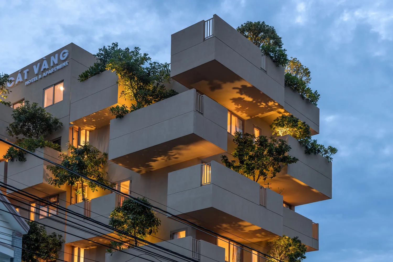 A modern apartment building with concrete balconies and illuminated windows.