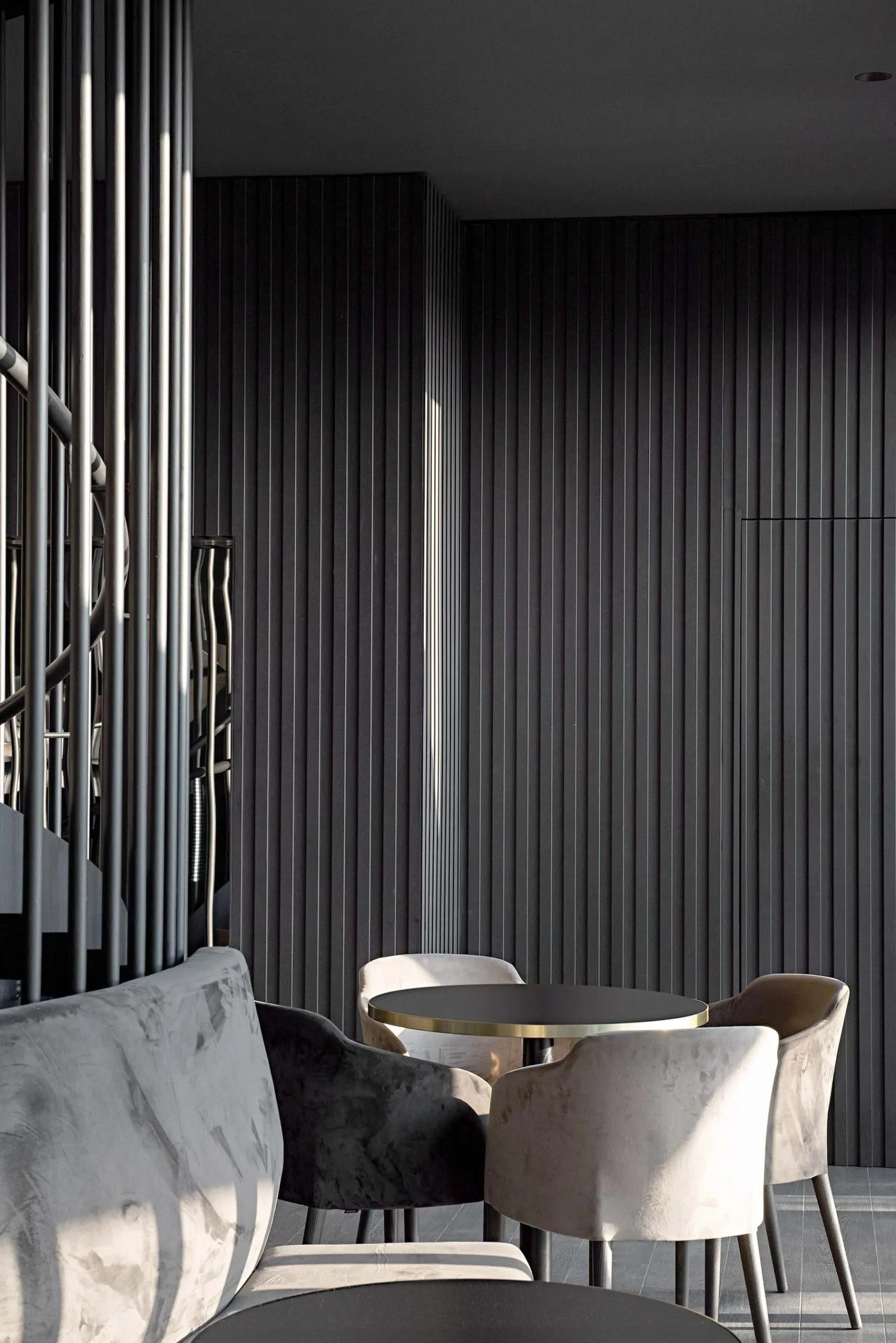 Modern cafe interior with black walls, plush velvet seating, and sleek steel accents.