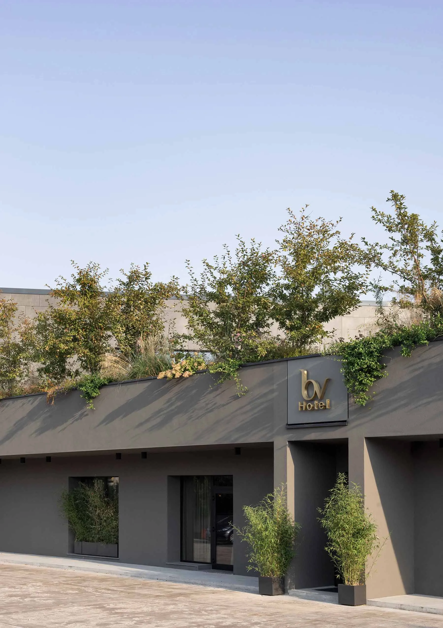 A modern hotel exterior with concrete walls and a green roof.
