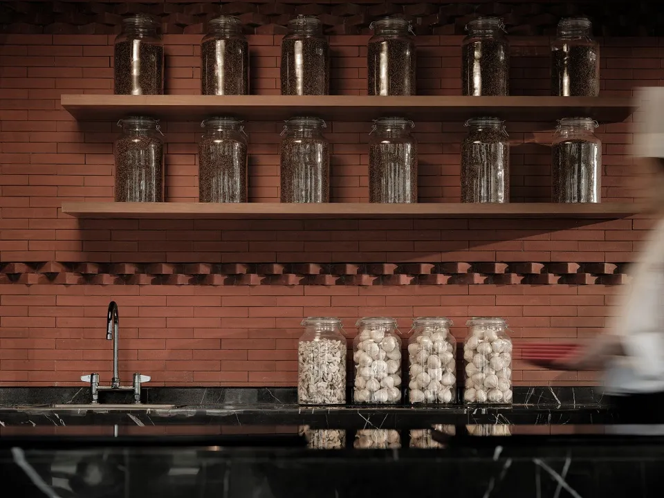 Modern kitchen featuring glass jars with food items on shelves and garlic on the countertop.