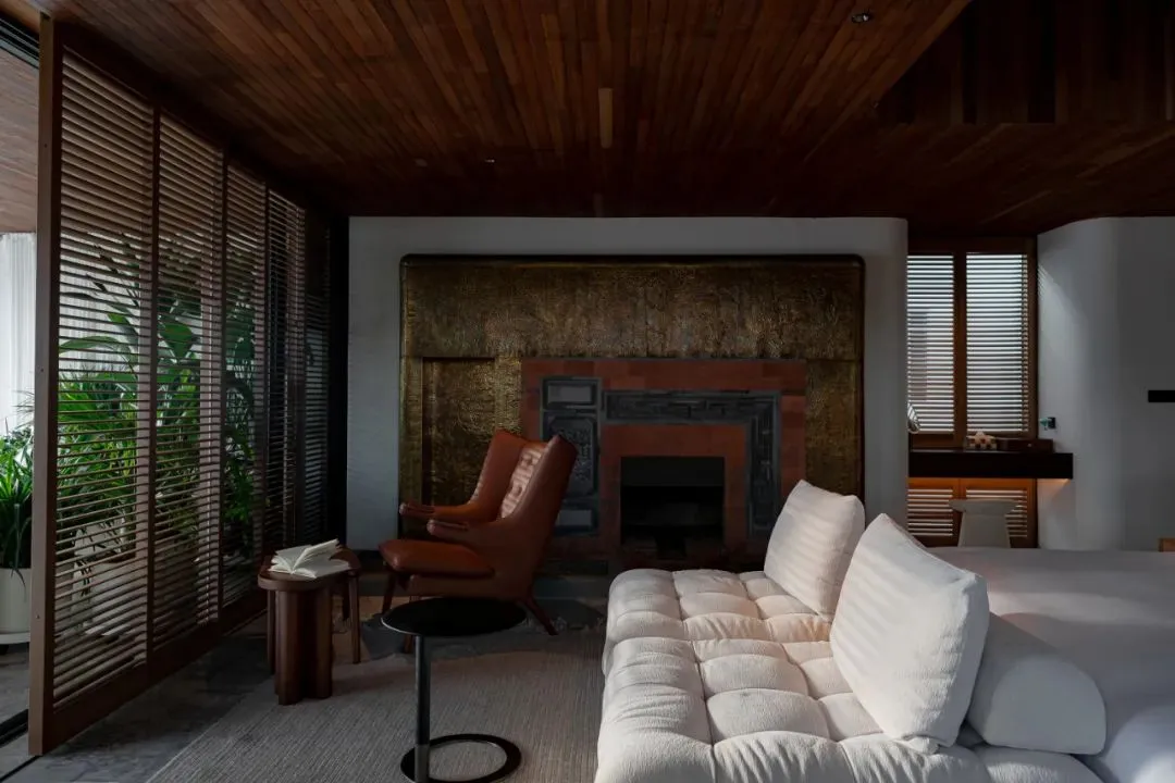 Modern living room with white couch, wooden ceiling, and fireplace.