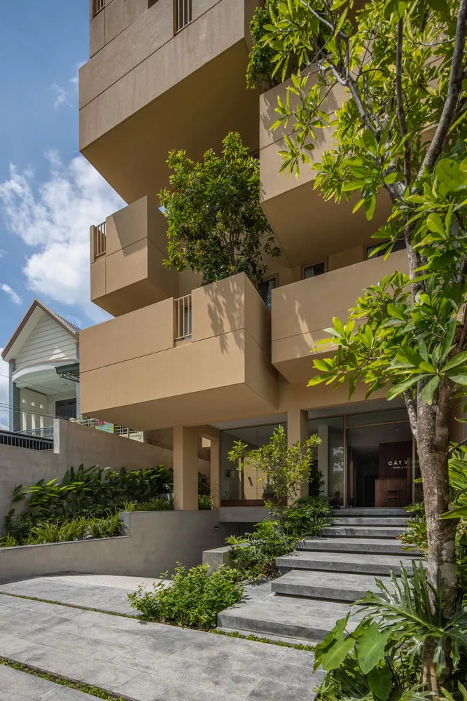 一座採用混凝土建築設計的現代住宅大樓，搭配綠意植栽。