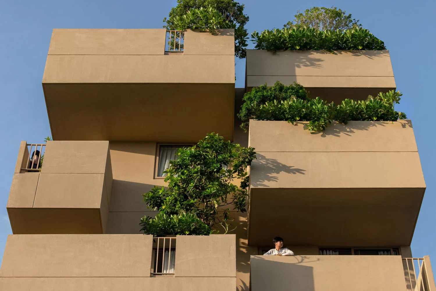 Modern residential building with concrete balconies and green plants.