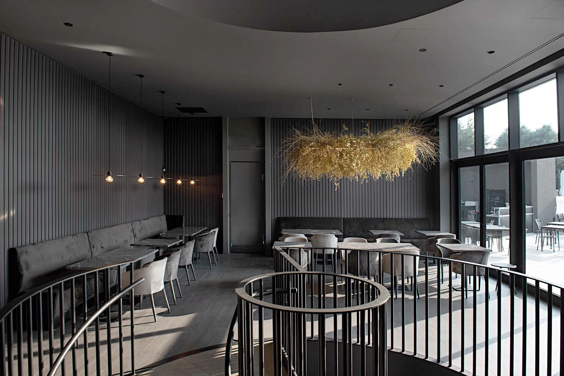 Modern restaurant interior with black and glass seating area and circular black railings.